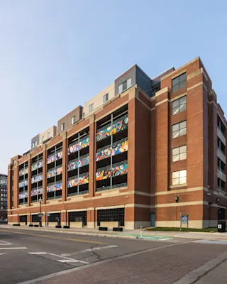 An exterior photo of River Place Garage in Detroit, showcasing the street and painted murals along the facade.