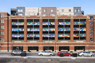 An exterior photo of River Place Garage featuring the entry/exit lanes and murals on the facade.