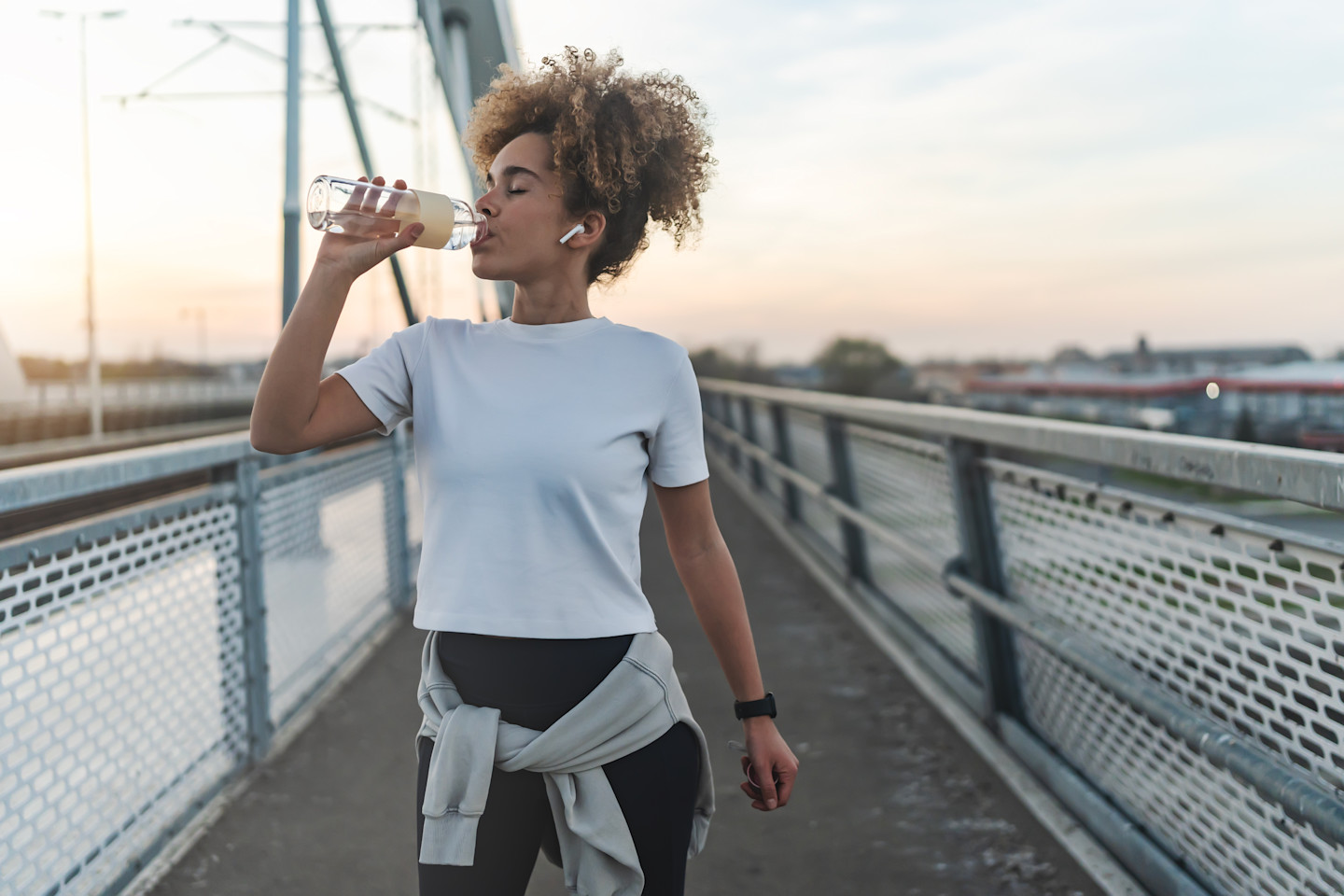 Visuel d'une femme qui boit une bouteille d'eau sur un pont
