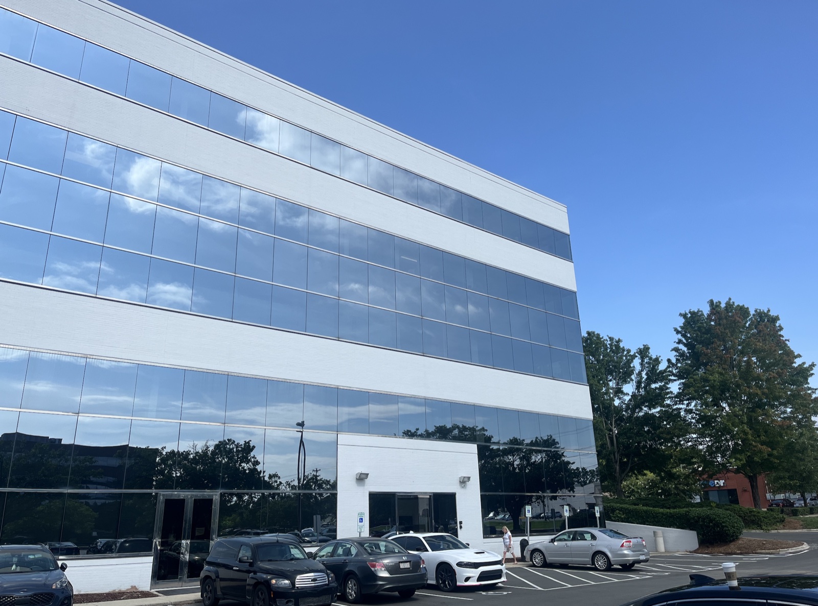 Exterior of the Shoeboxed headquarters office building, a multi-story glass-walled building with reflective windows and parked cars in the foreground