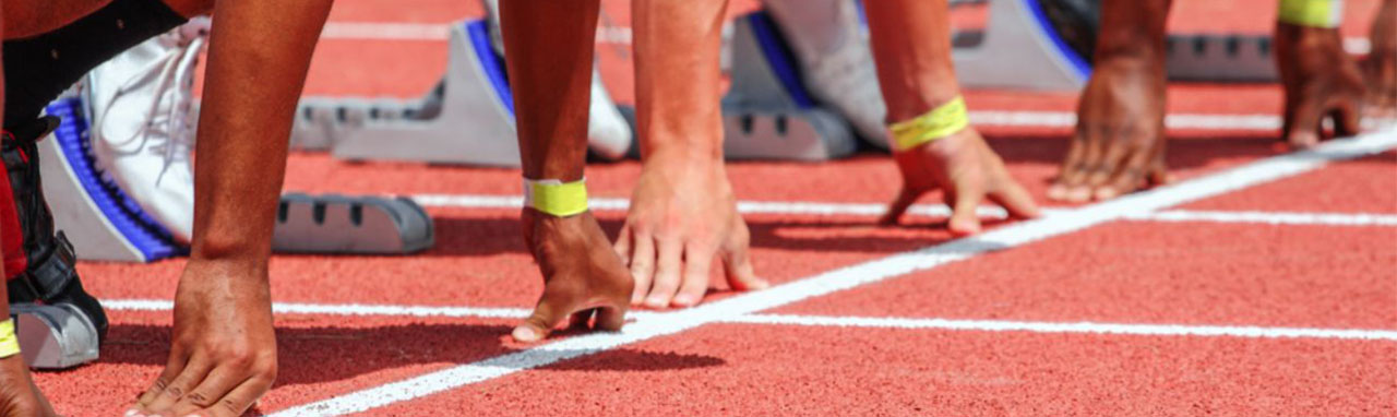 Gros plan sur les mains d'athlète s'apprétant à prendre le départ d'une course d'athlétisme