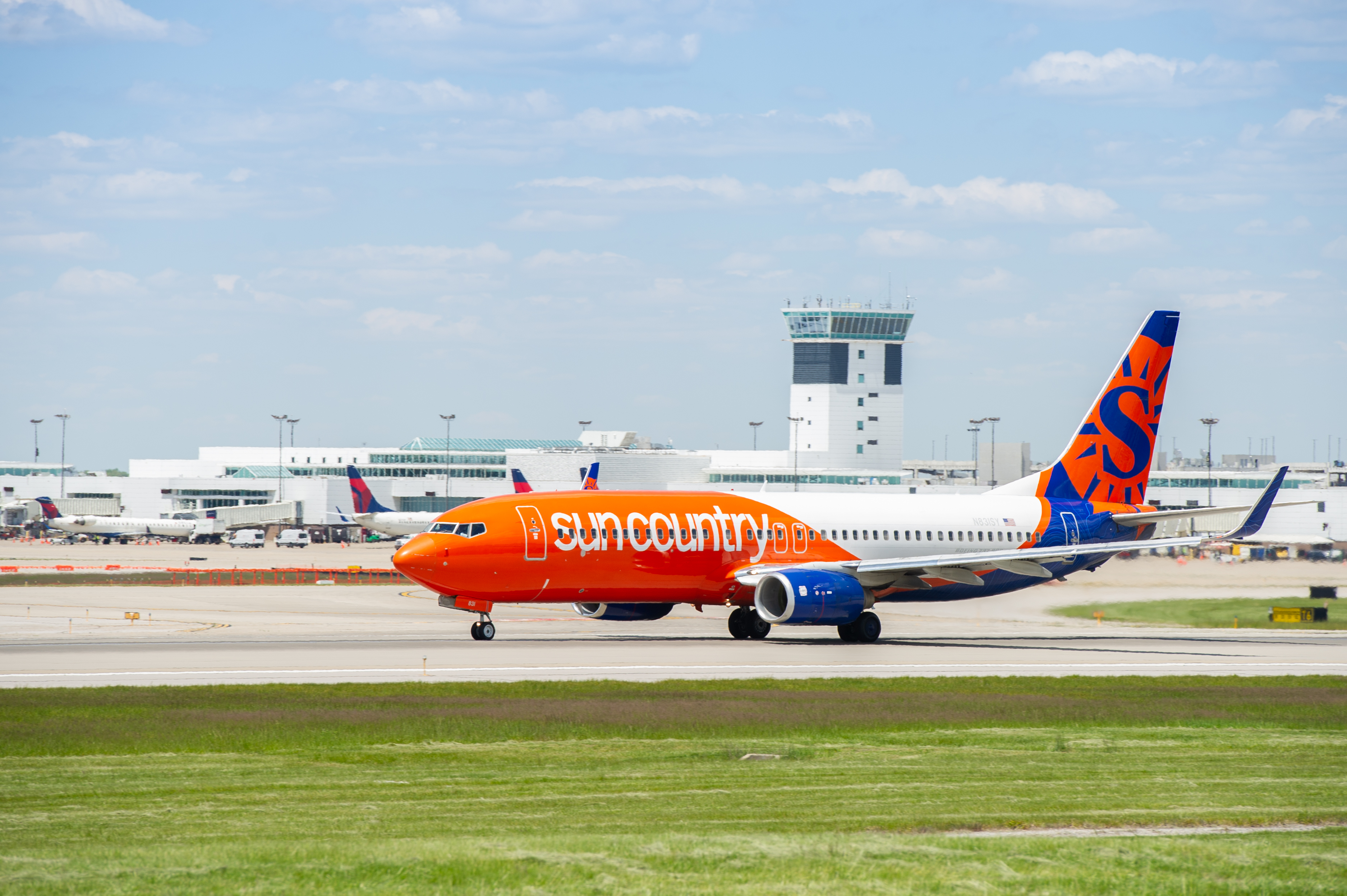 A photo of a bright orange Sun Country plane taxiing. 