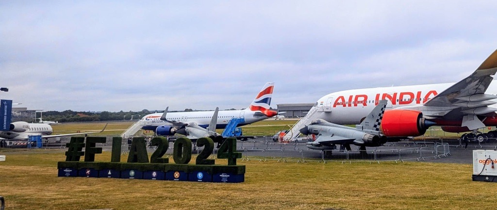 A photo of multiple planes behind a sign that reads #FIA2024.