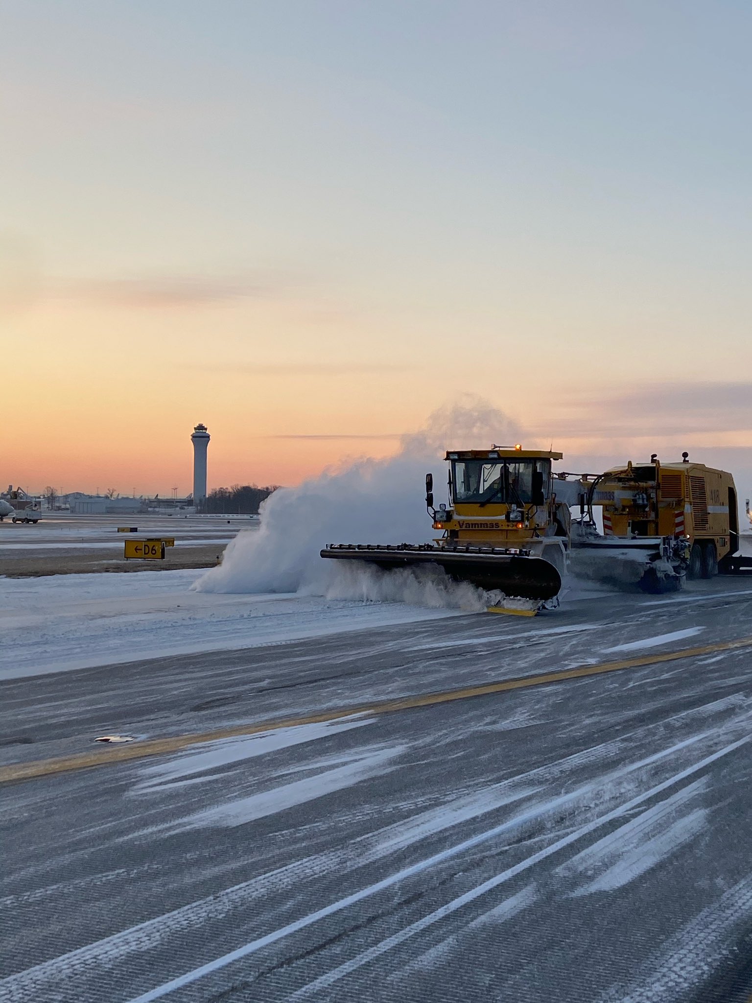 A snowplow clearing the pavement around the airfield.