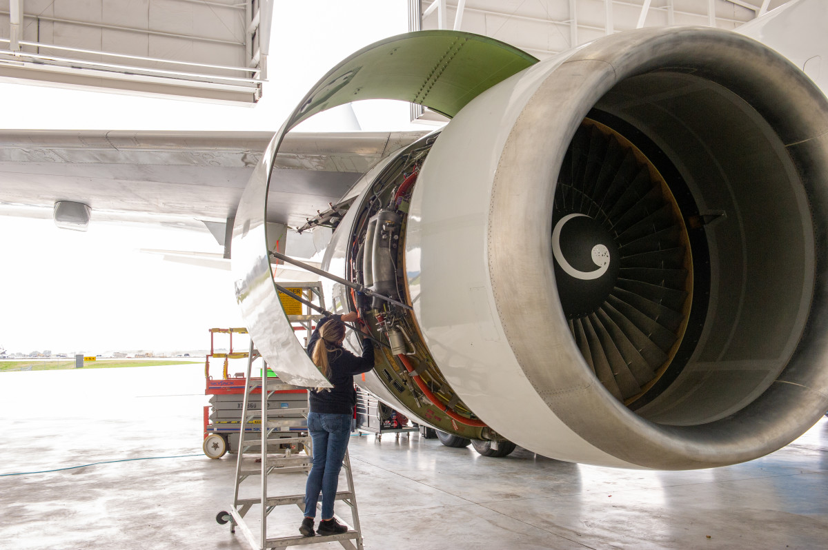 A photo of an Aviation Mechanic working on a plane engine.