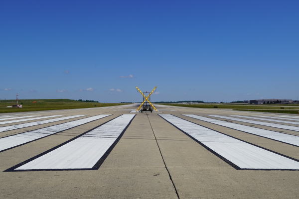 A photo looking down runway 18C with a giant X standing up in the middle of the runway to mark the closure.