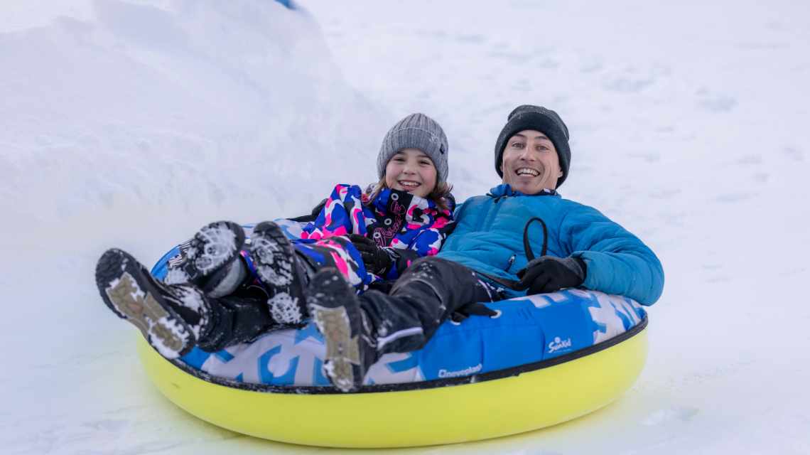 Man and child snowtubing in Ginzling