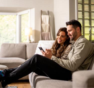 couple-on-couch-looking-at-phone-mobile