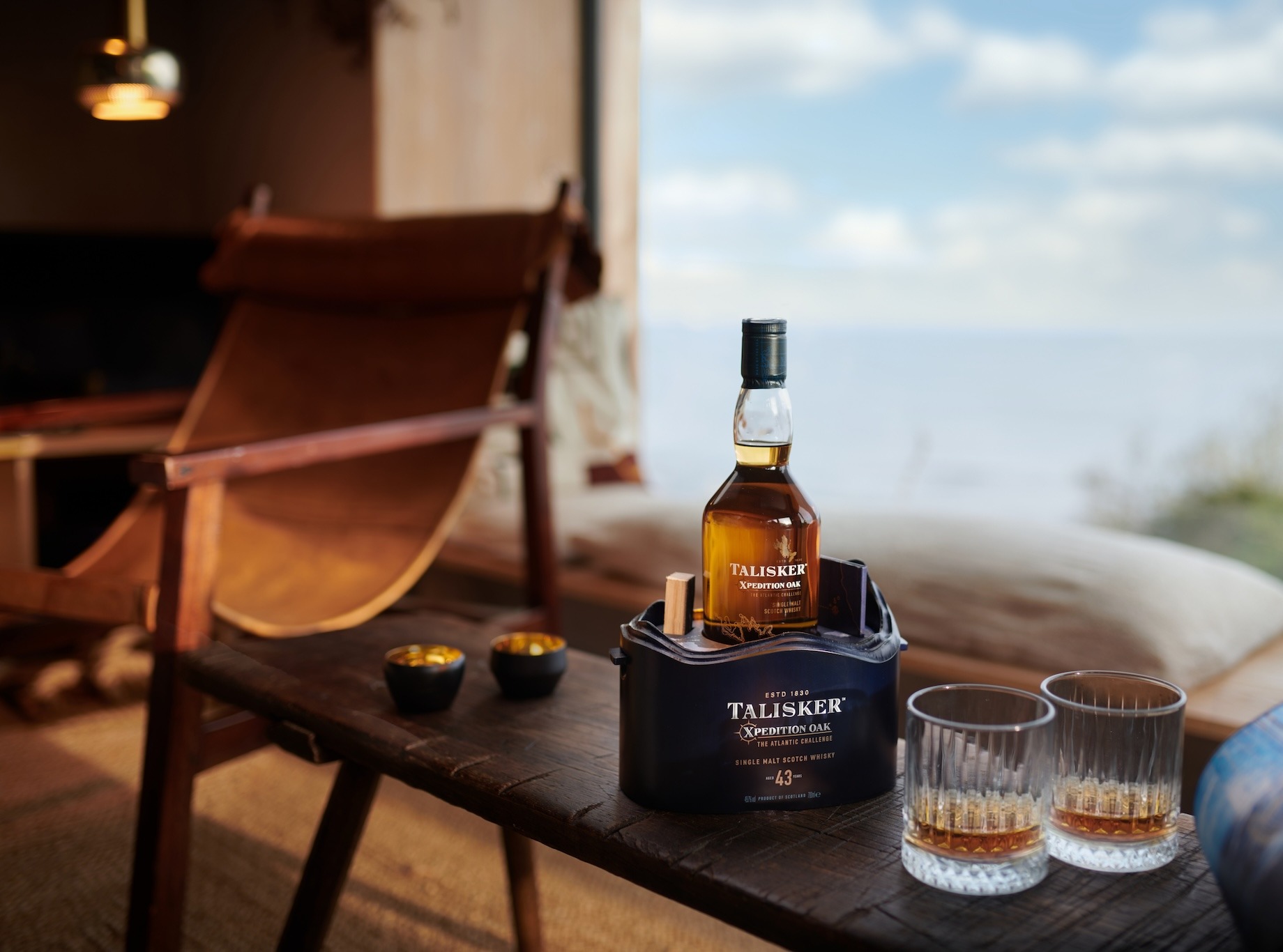 The image features a bottle of Talisker Xpedition Oak 43-Year-Old Single Malt Scotch Whisky placed in a unique,