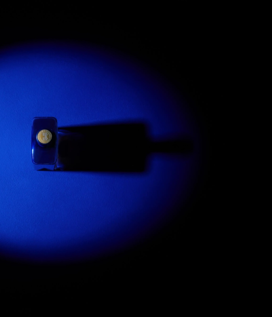 A blue light casts a glow on the top of a Mortlach 30-year-old bottle, captured from a top-down perspective