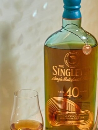 A bottle of The Singleton 40-Year-Old Single Malt Scotch Whisky is placed on a countertop, flanked by two whisky glasses filled with amber liquid. 