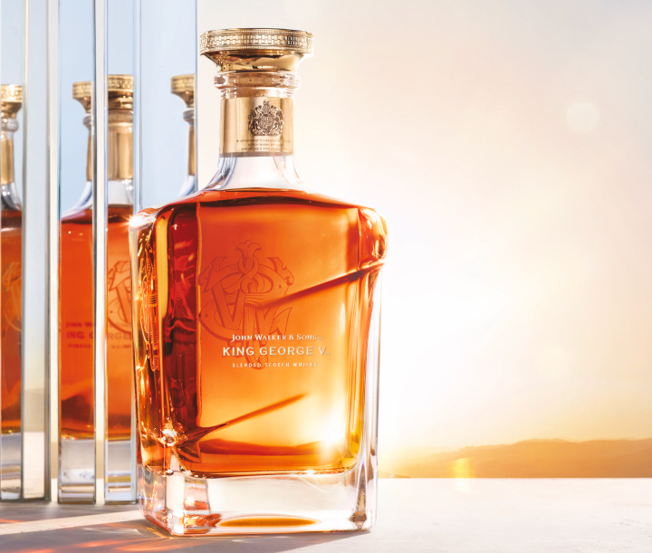 A premium bottle of John Walker & Sons King George V Blended Scotch Whisky, set against a glowing sunset. 
