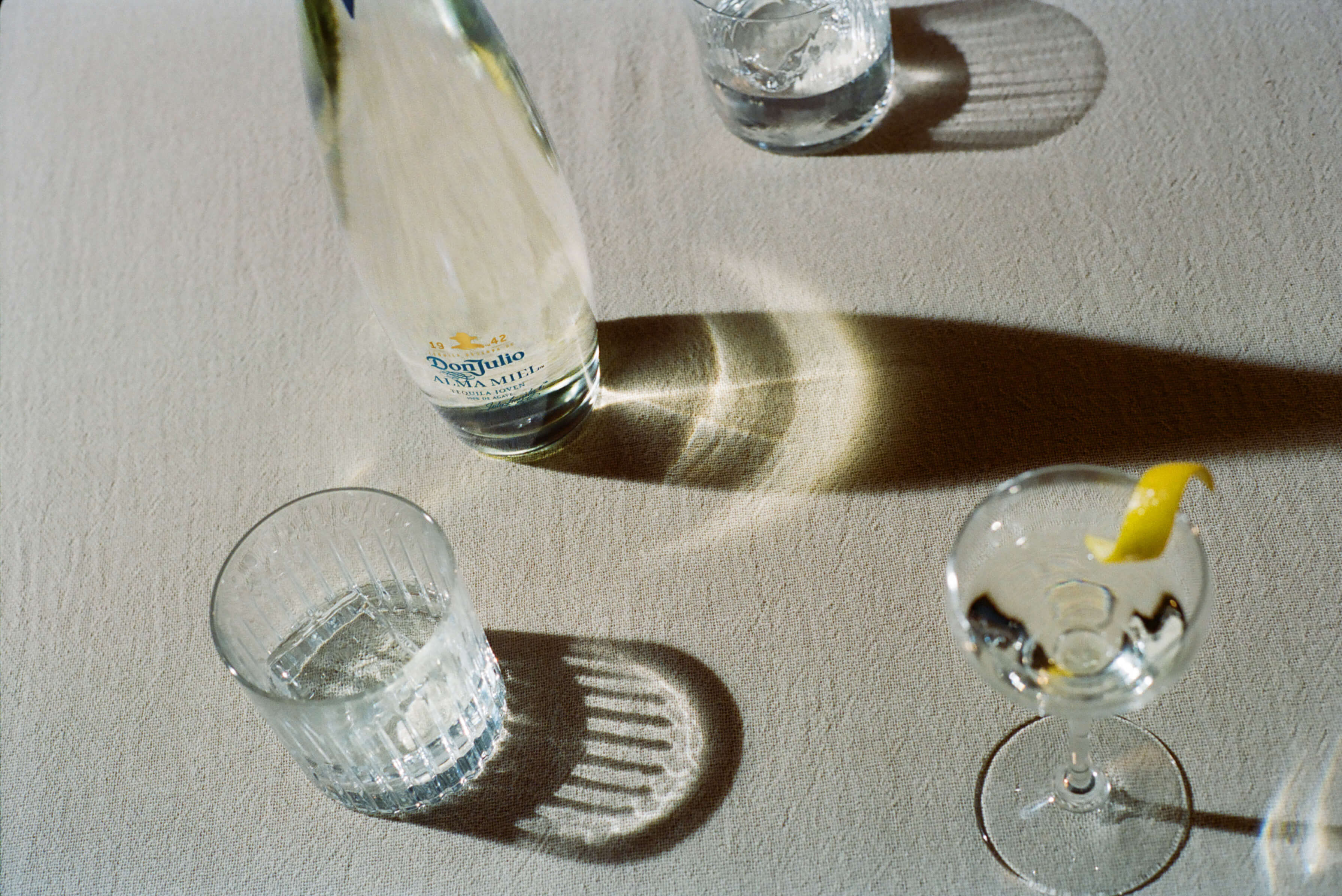 A top-down shot of a bottle of Don Julio Alma Miel tequila placed on a textured nuetral-coloured surface.