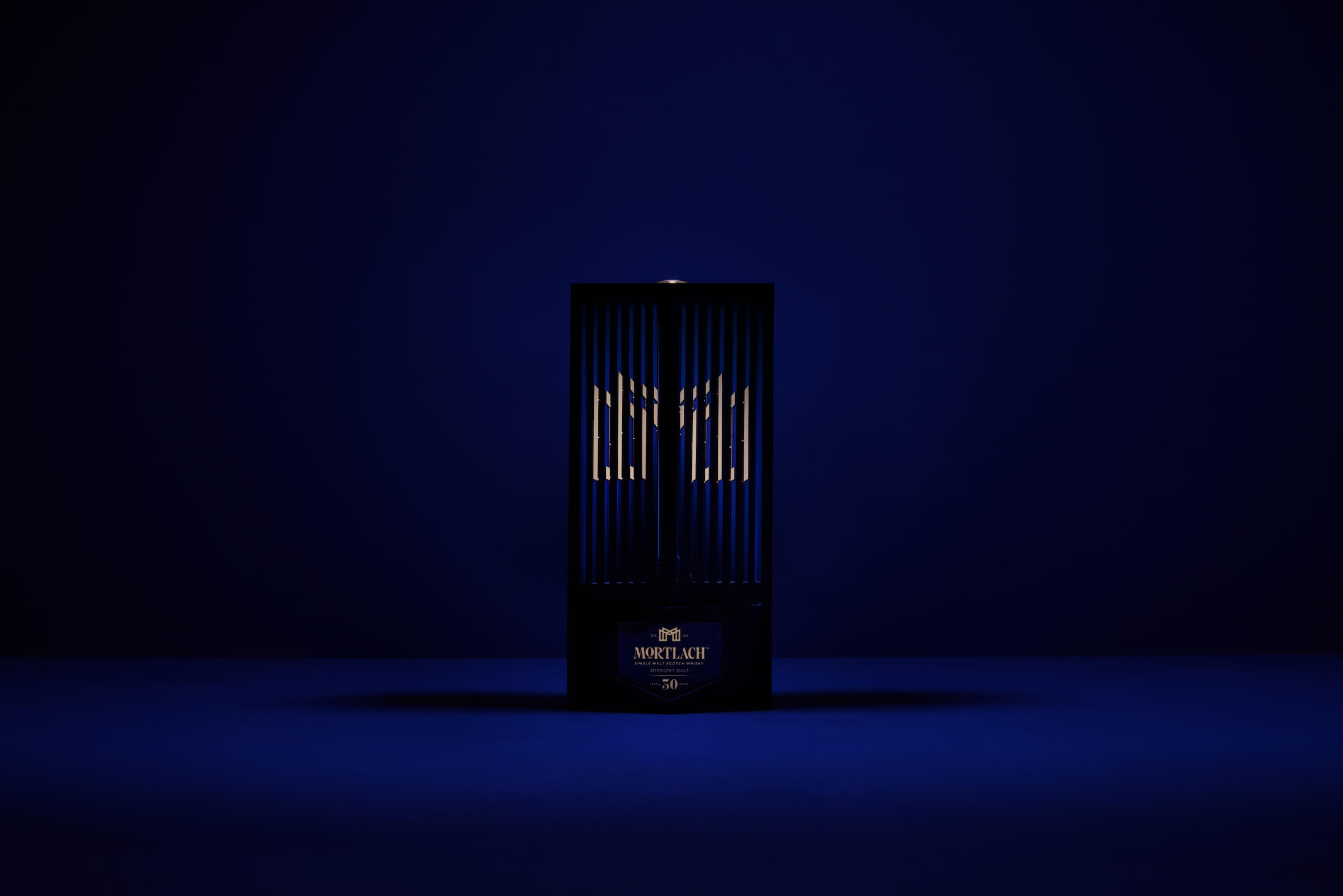 A dark blue, minimalist setting showcases the Mortlach 30-Year-Old Midnight Malt box