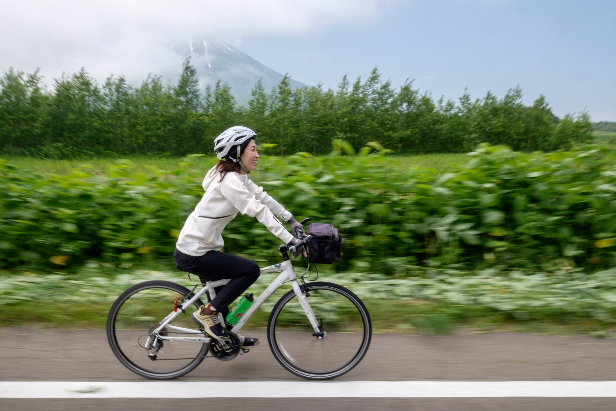 A cyclist rides past Mount Yotei