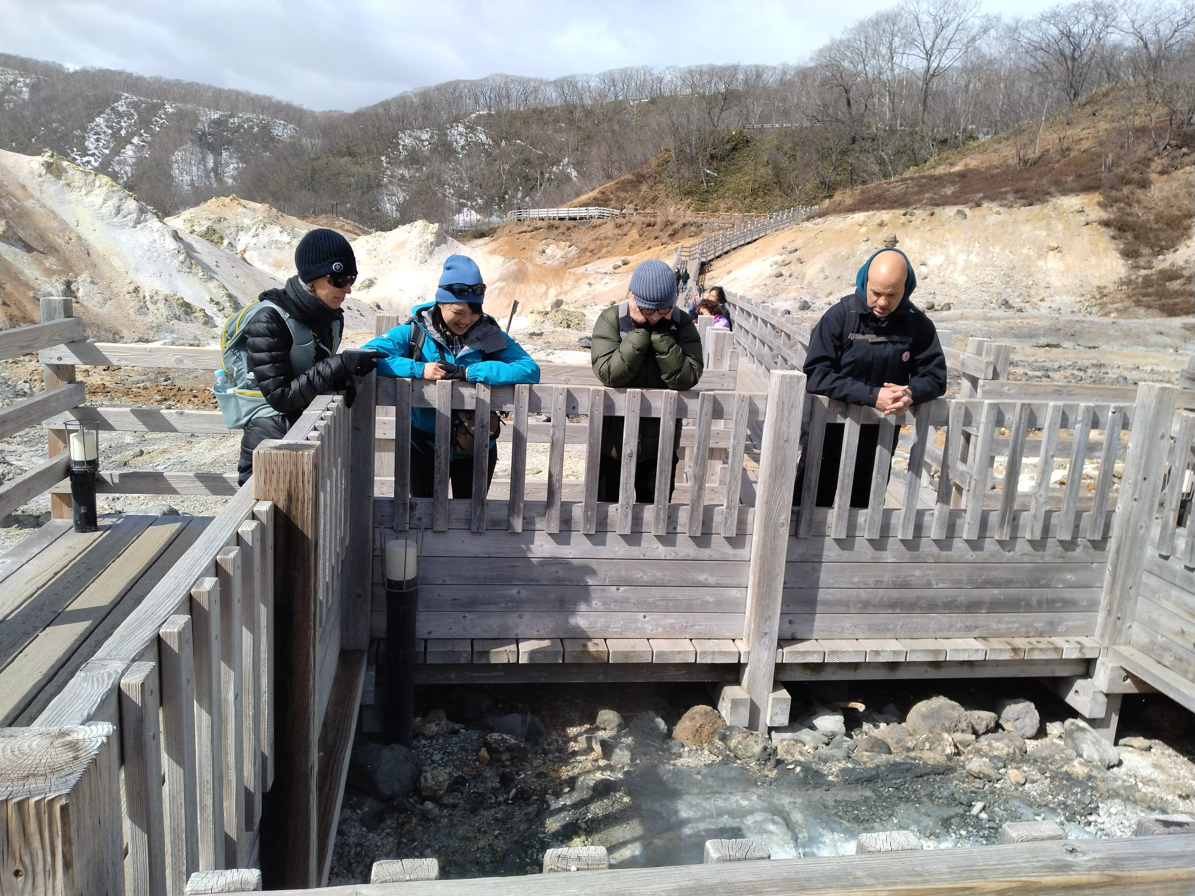 Yuka and three guests look into a hot spring pool at Noboribetsu Hell Valley.