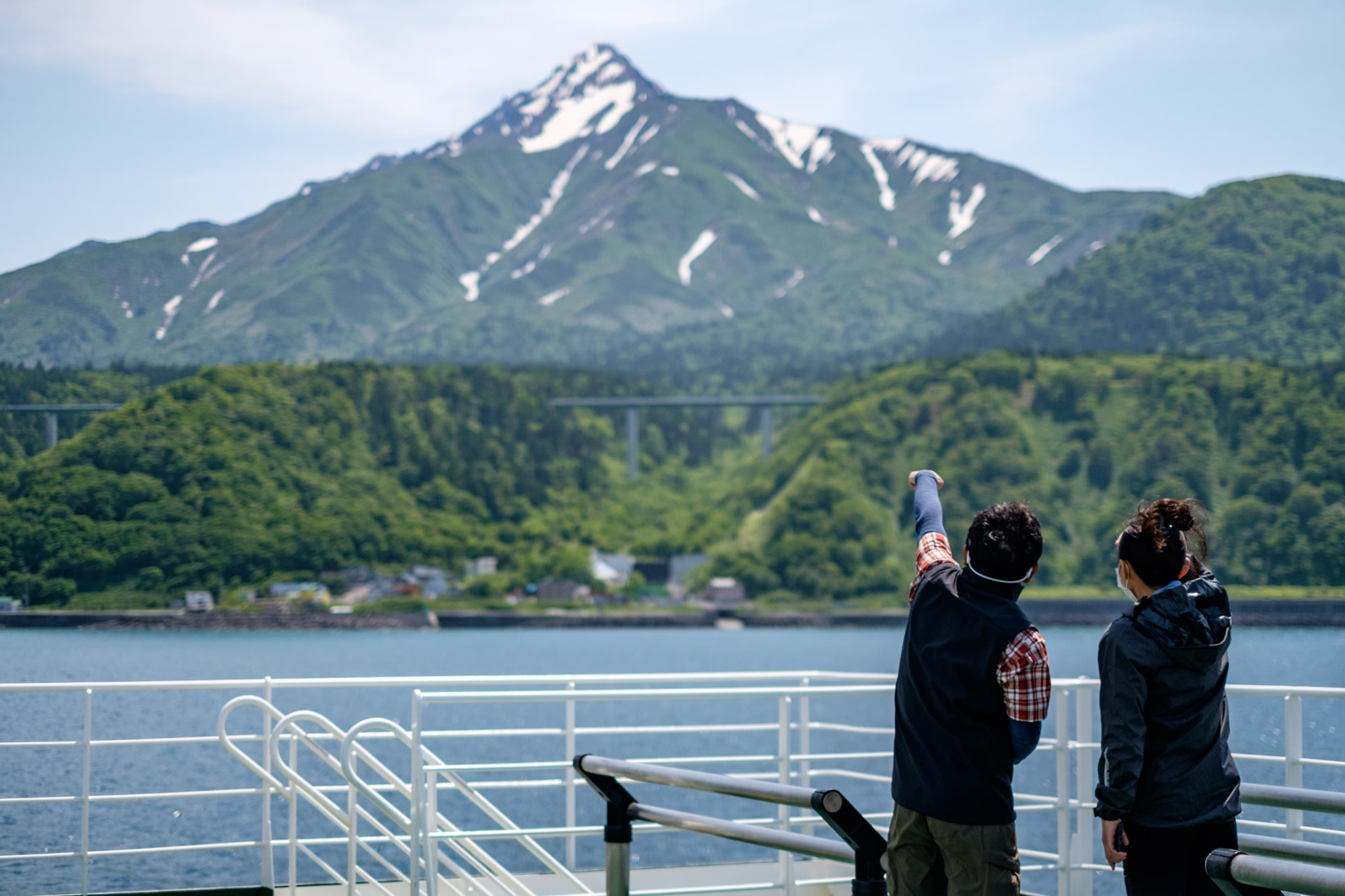 A guide points to Mount Rishiri from a ferry
