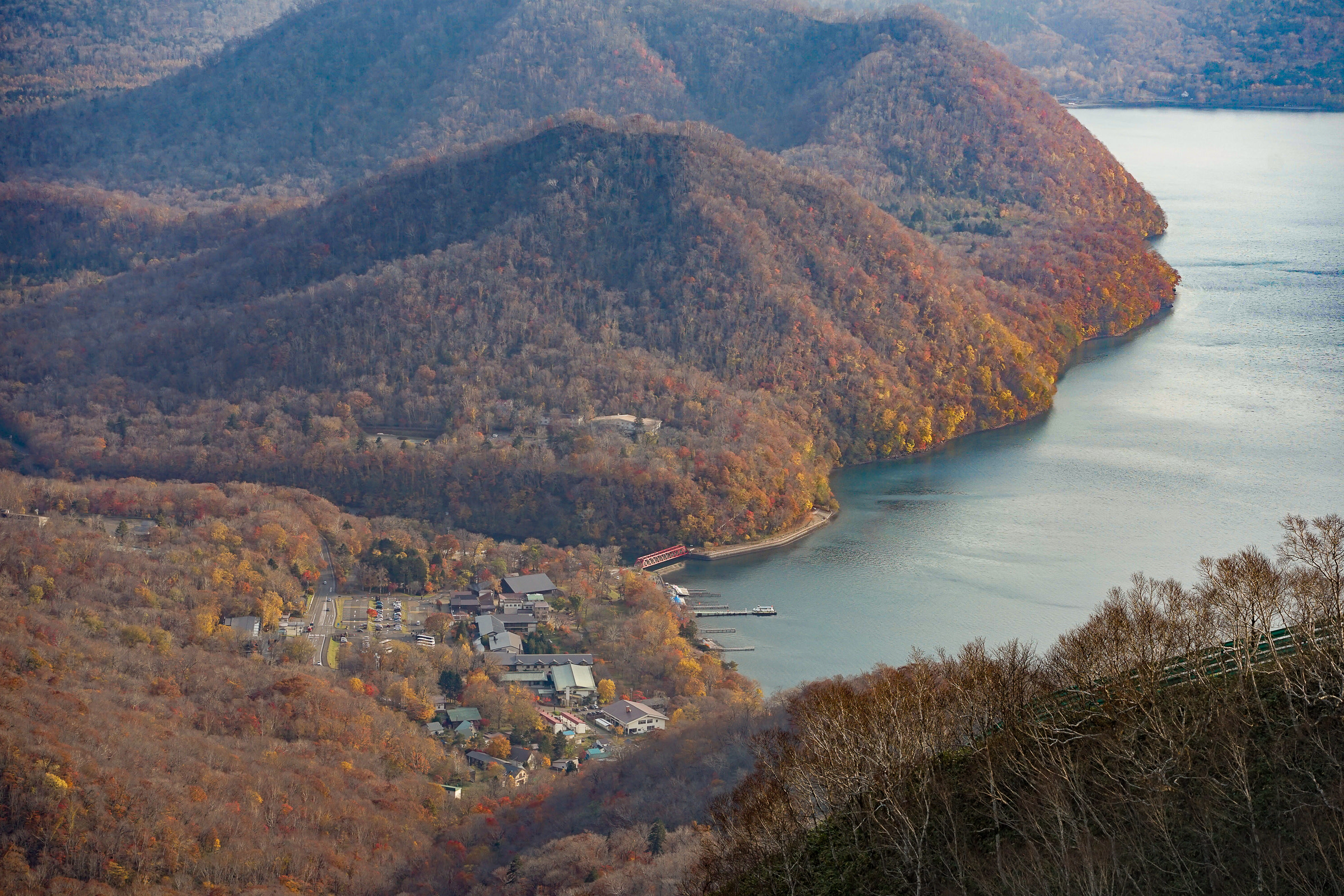 A shot of Lake Shikotsu's shore from Mt. Monbetsu's trail. The hills and mountains are a curious mixture of orange, red and brown.