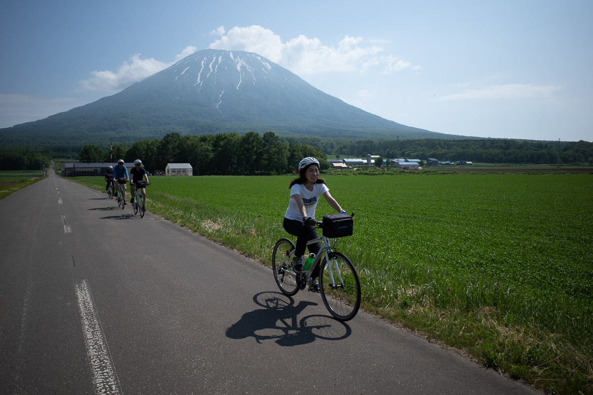 Cyclists on a country road with Mt. Yotei in the background.
