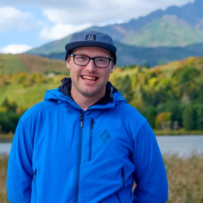 Adventure Hokkaido Guide Richard smiles to the camera while standing in front of a view of Mt Rishiri