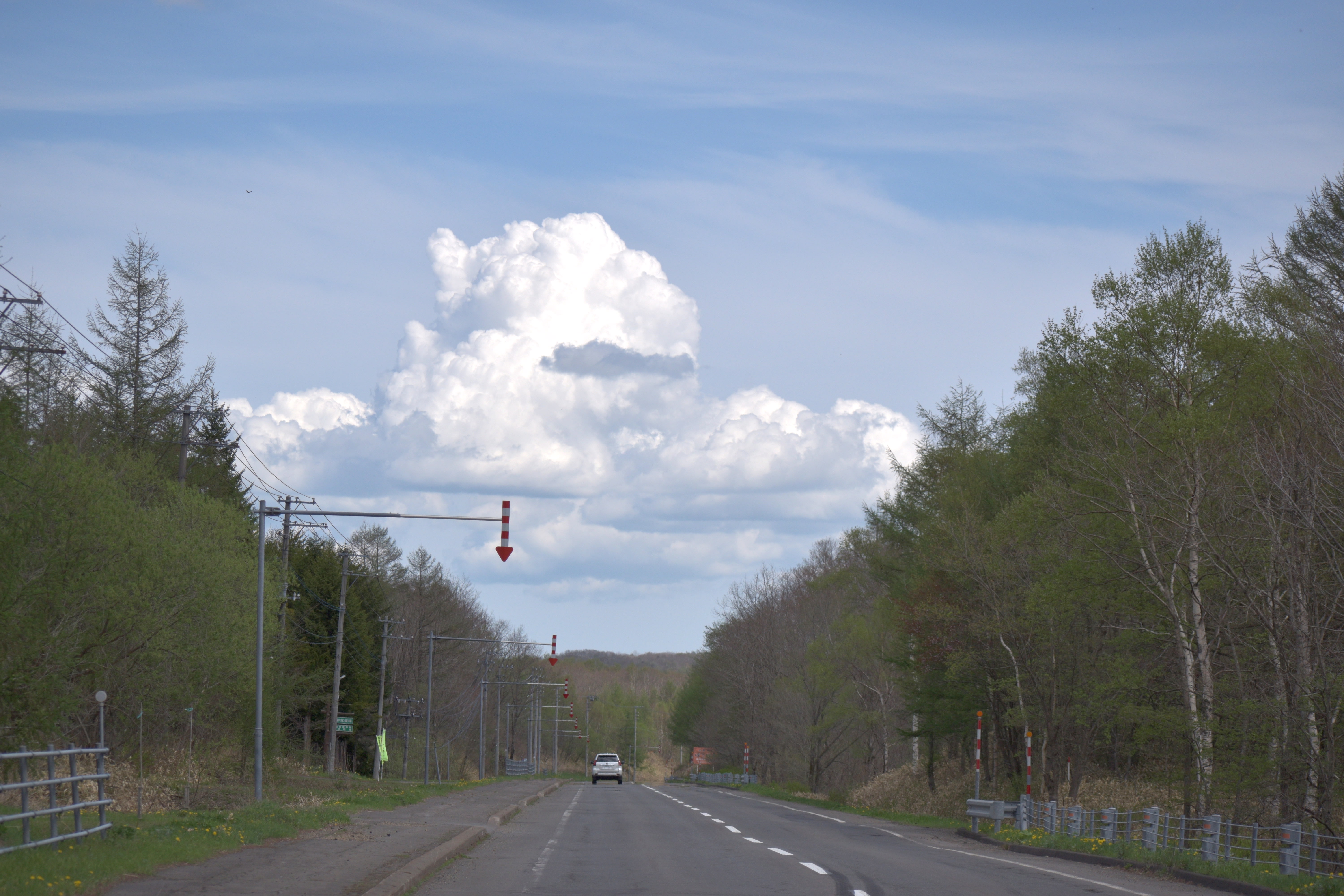 A road in Teshikaga with a prominent cloud formation in the sky.