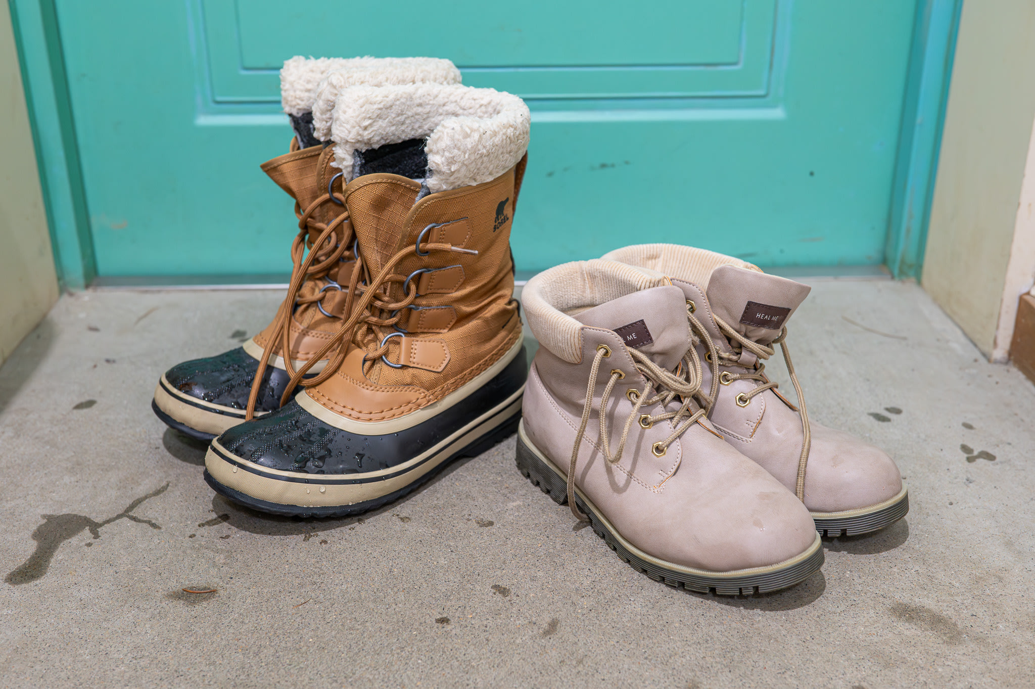 Two pairs of boots on a concrete floor. Both are snow boots, but one is high-cut and the other low-cut.