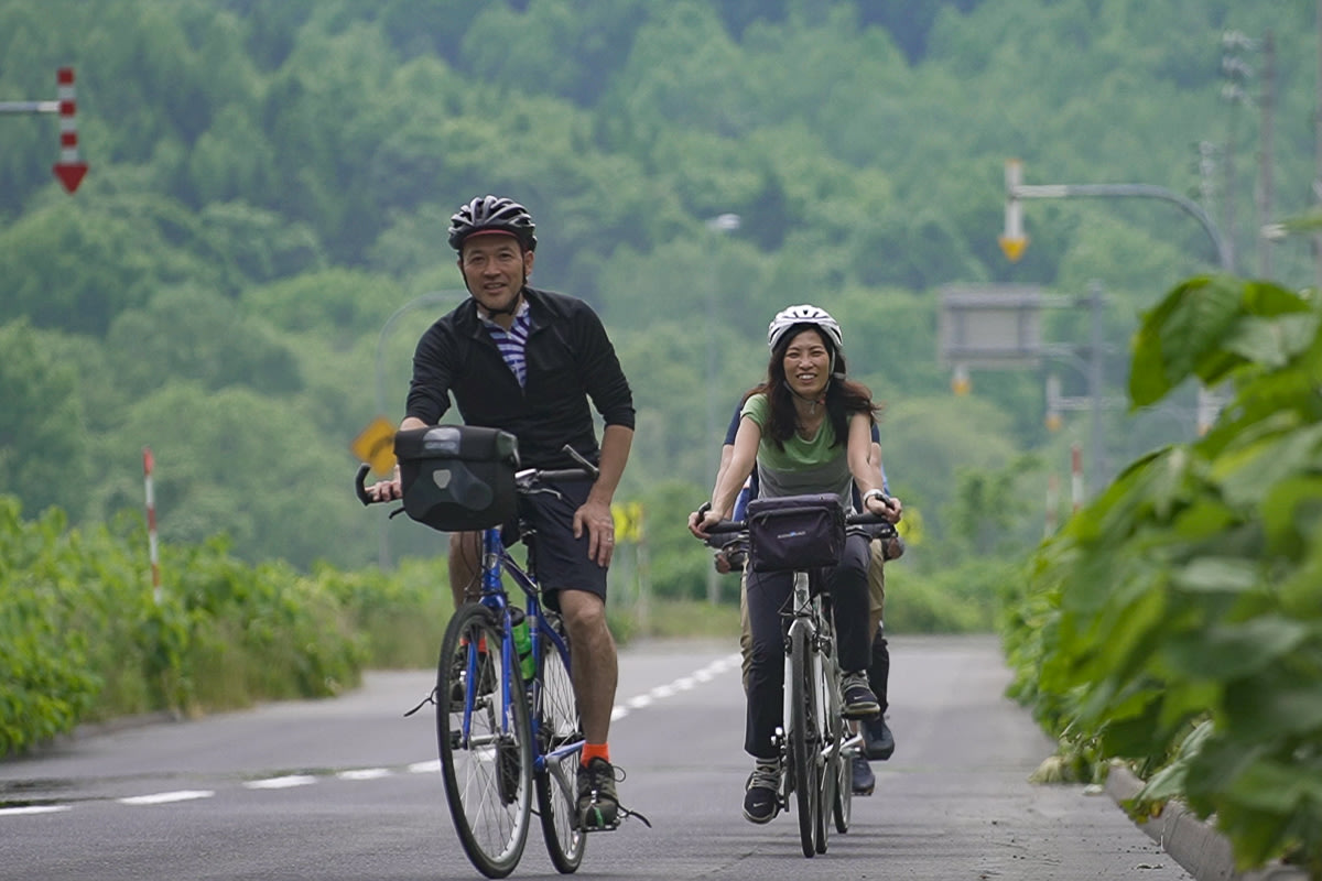 Cyclists riding through greenery near Lake Toya, Hokkaido