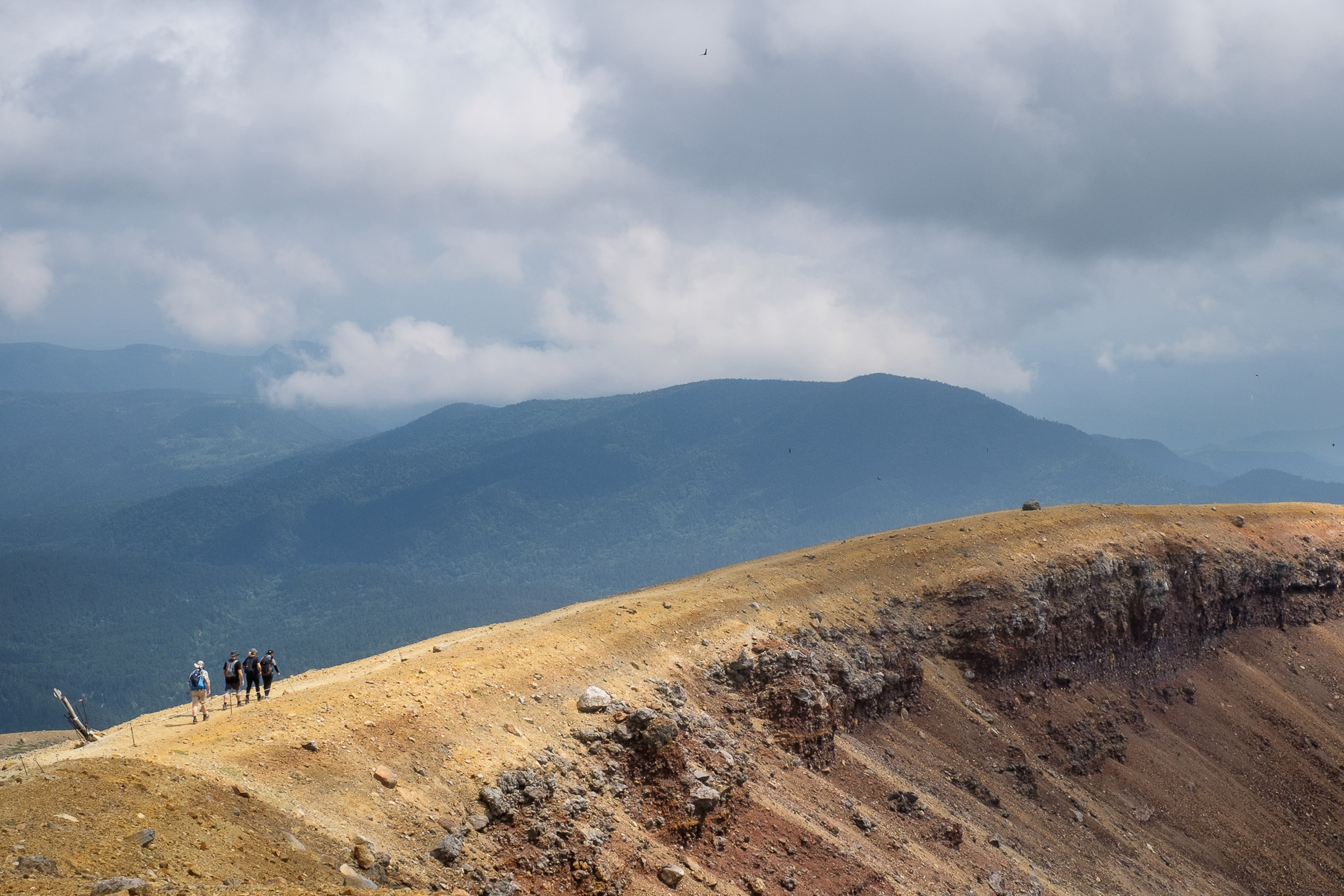 A group of hikers walk along the ridge of Mt. Meakan on a cloudy day.