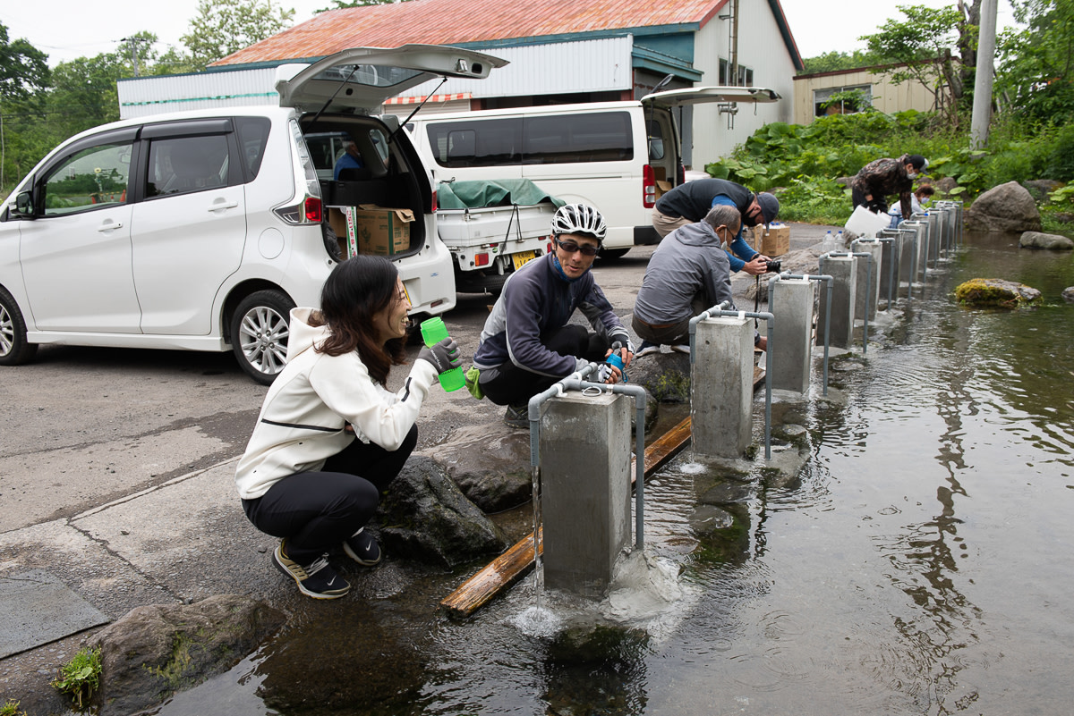 Cyclists filling their water bottles at a natural spring