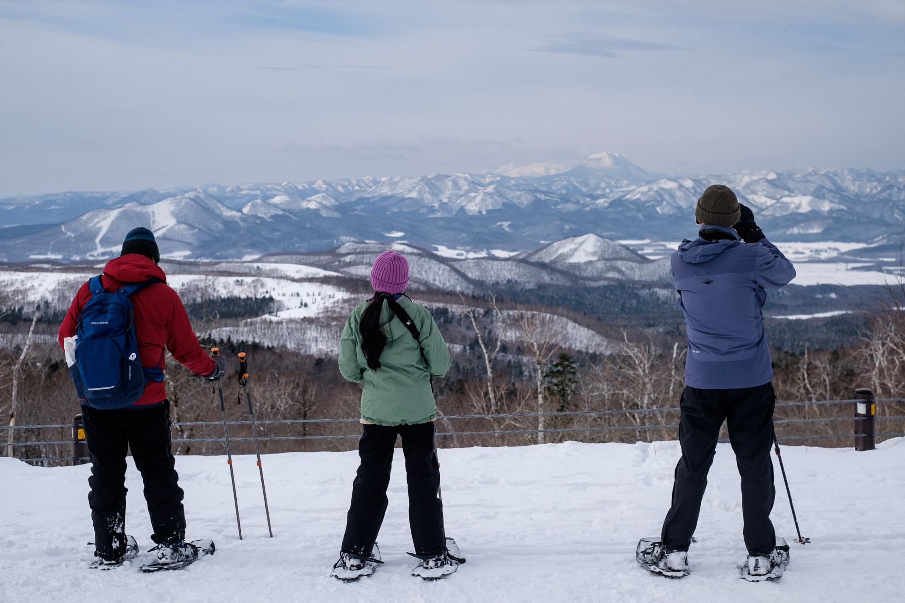 A group of snowshoers take in the views from Lake Mashu towards Mt. Oakan