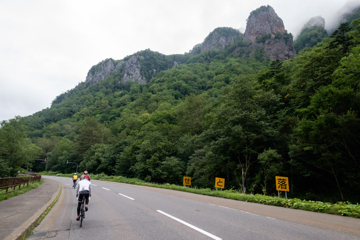 A cyclist rides past jagged rock formations in Sounkyo, Hokkaido