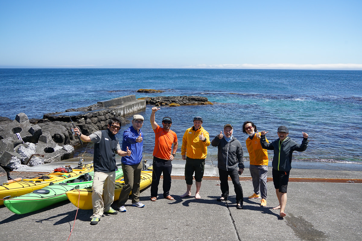 A group of kayakers pose by the sea