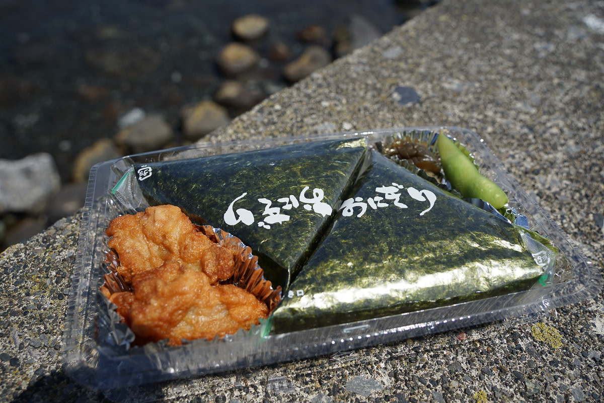 A lunchbox containing rice balls and friend chicken