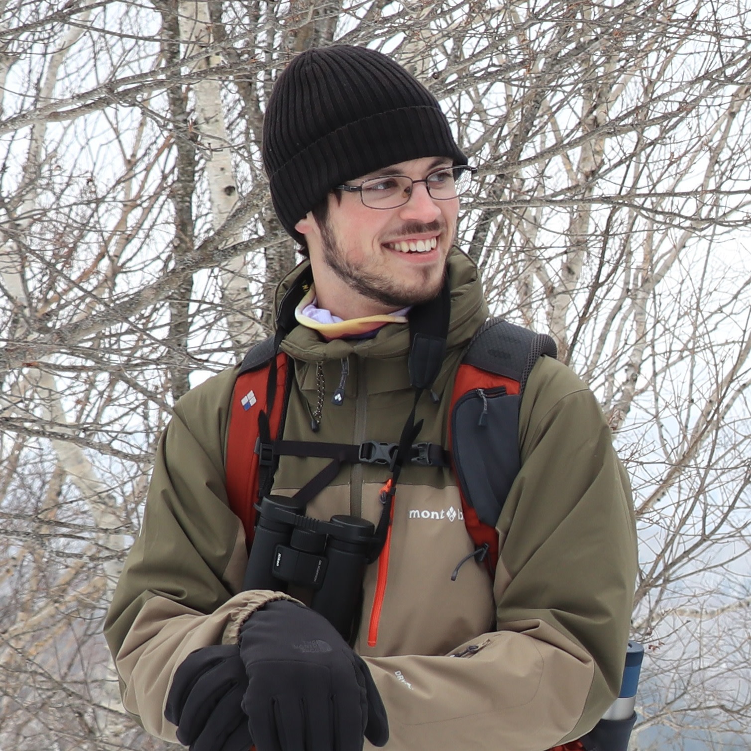 Adventure Hokkaido guide Zac stands in front of birch trees. It's winter and the trees have no leaves.