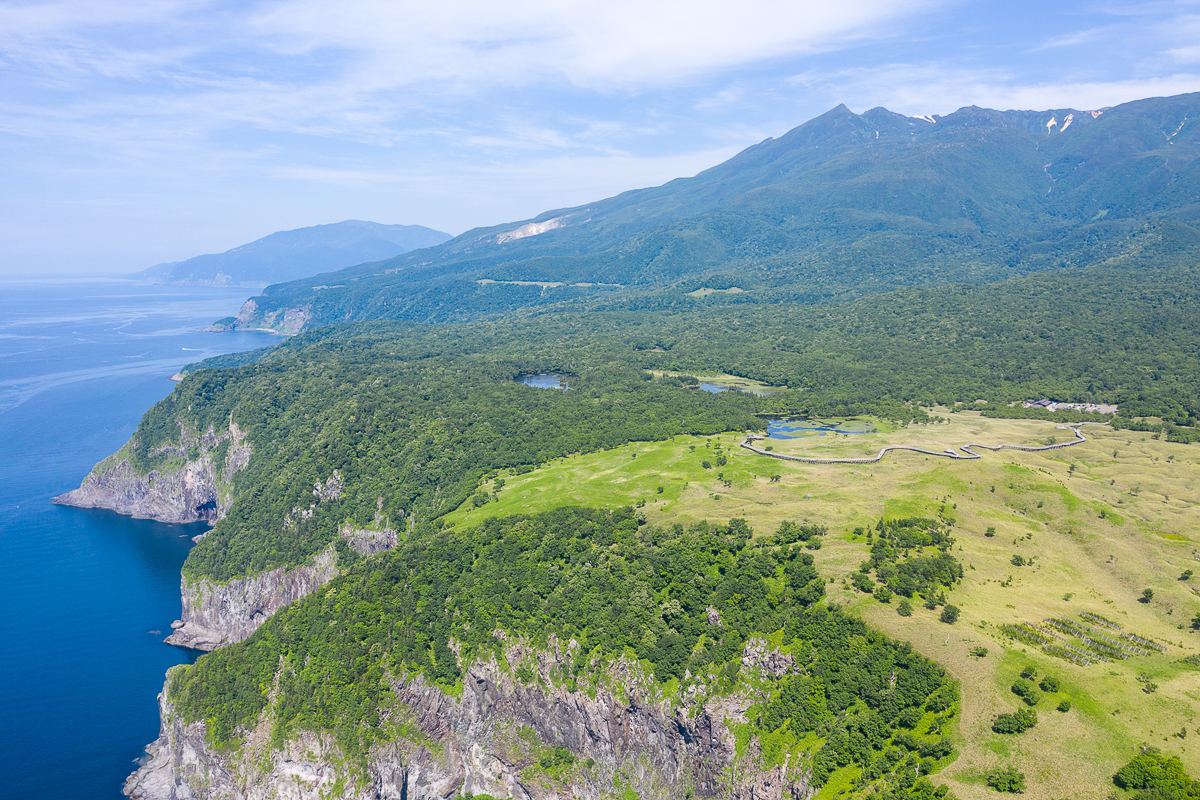 An aerial shot of the Shiretoko 5 Lakes area. Green wilderness covers the area from the mountain peaks tumbling almost all that way into the ocean.