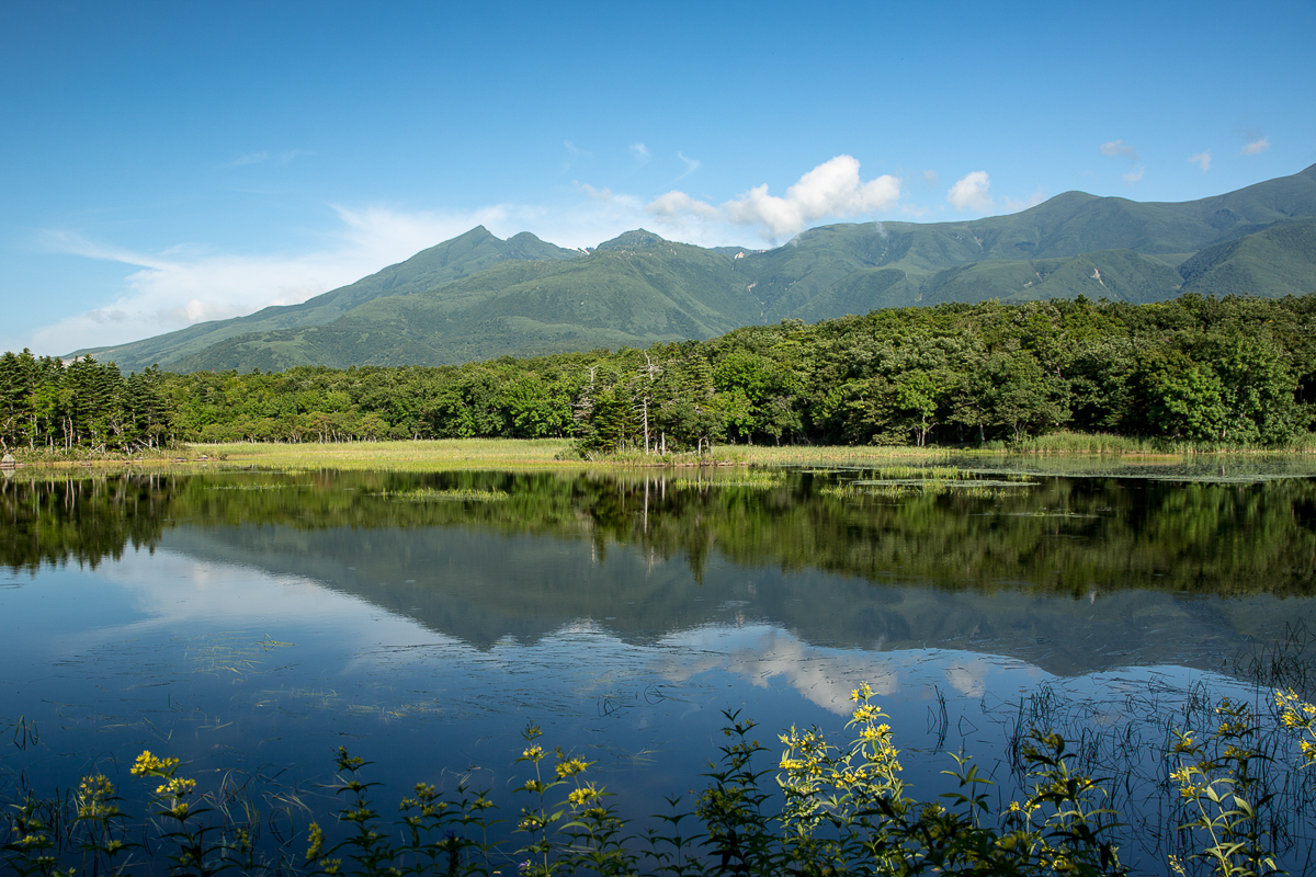A view of mountains in summer reflected in one of the Shiretoko Five Lakes.
