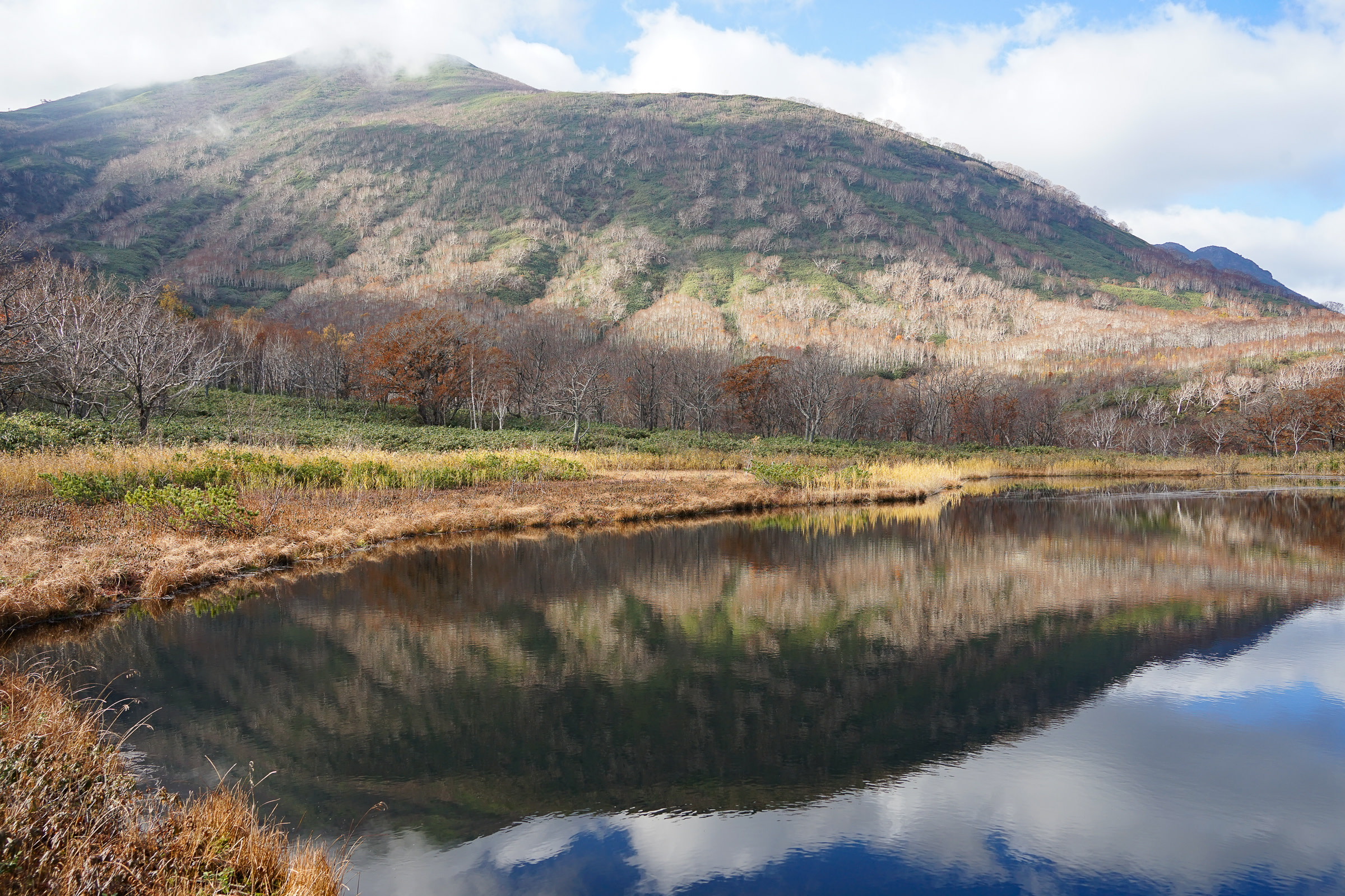 A view of Kagami Pond in Niseko. A mountain is perfectly reflected in its still surface.