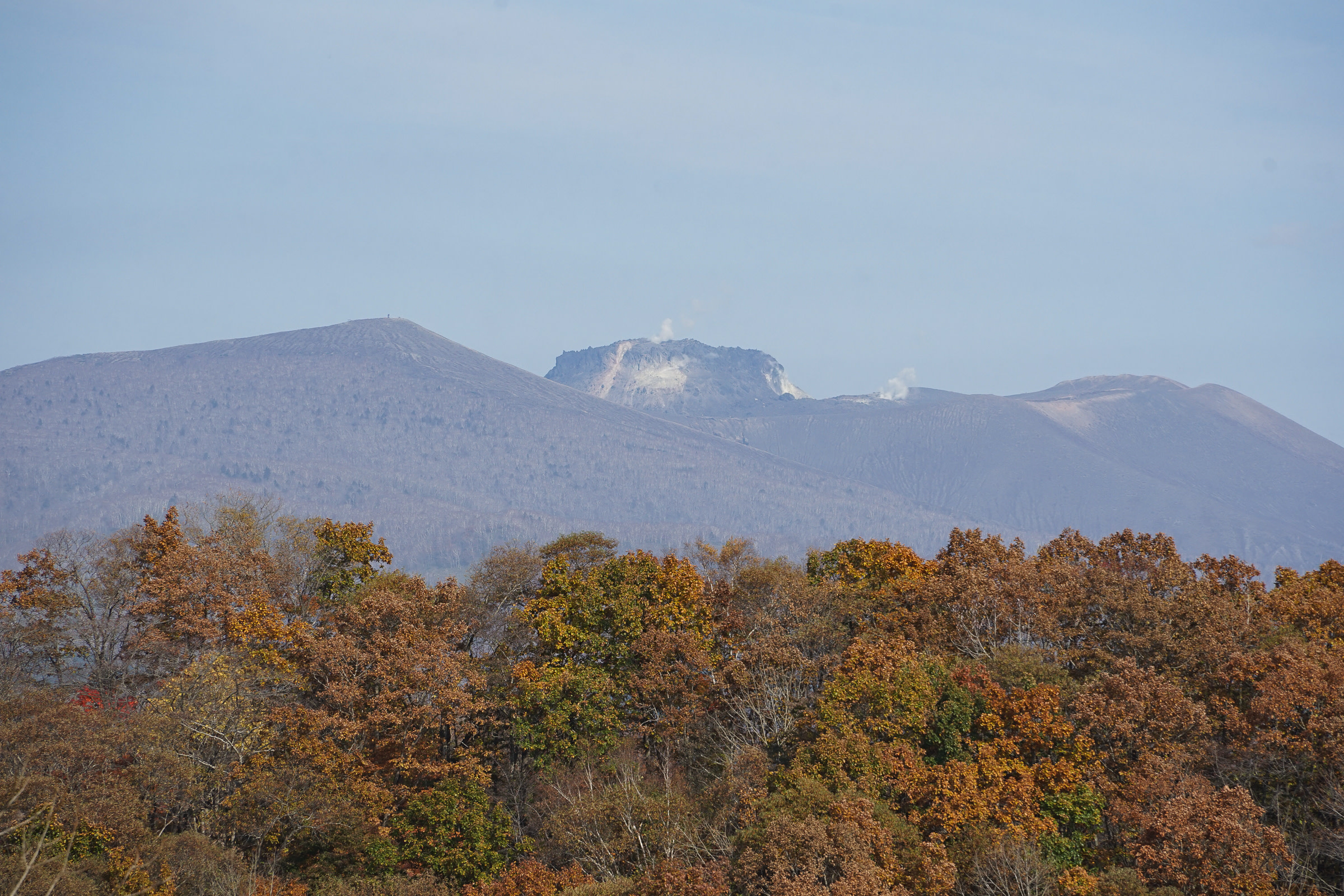 A view of the volcanic peak of Mt. Tarumae, as seen from Poroto Recreational Forest. Steam rises from its peak.