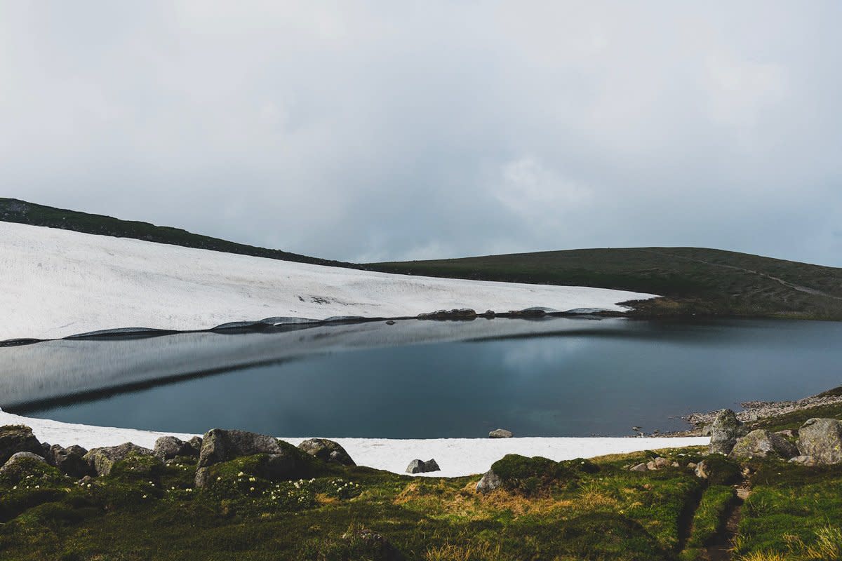 A blue pond surrounded by snow.