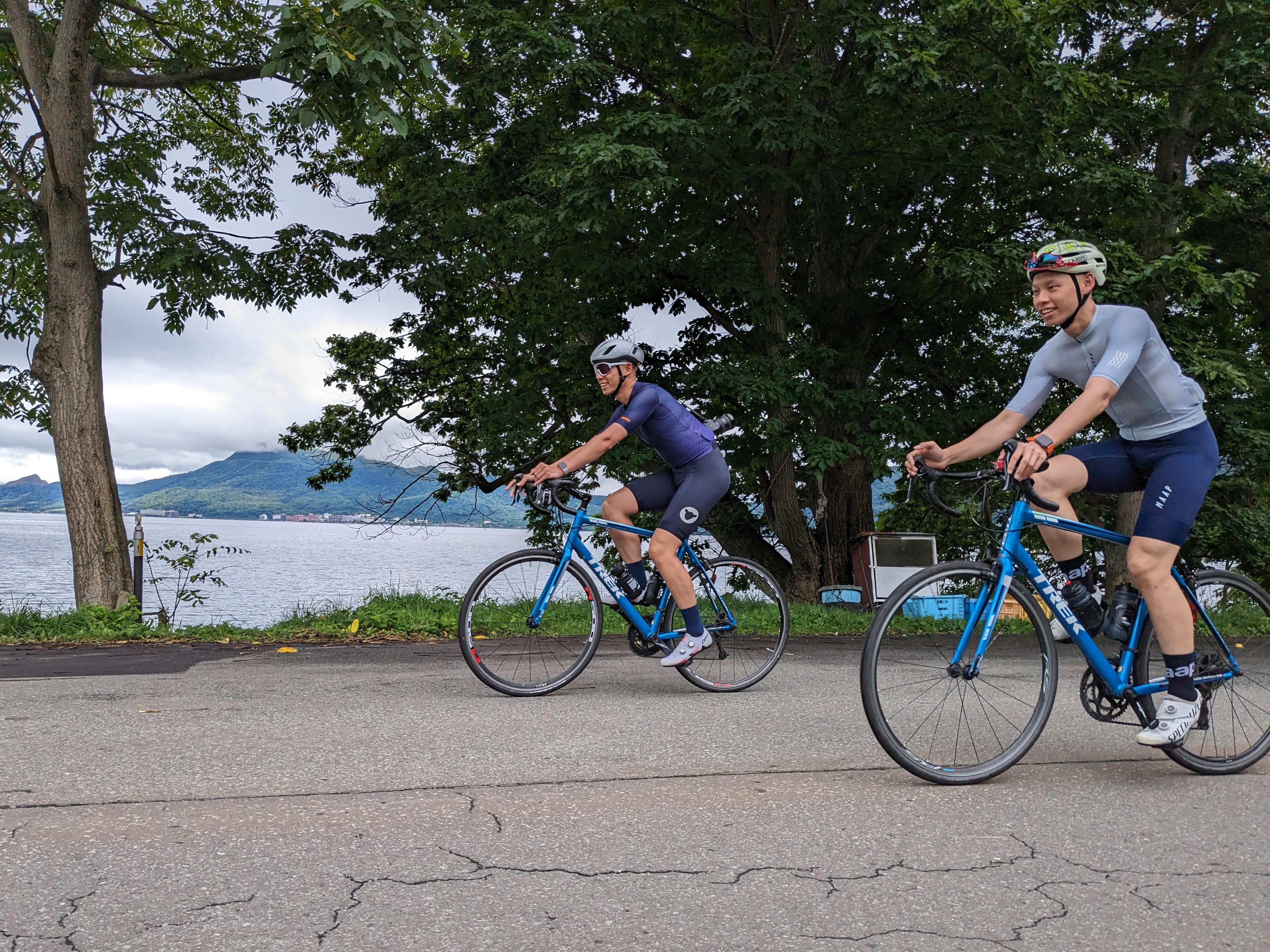 Two cyclists smile as they cycle along Lake Toya.