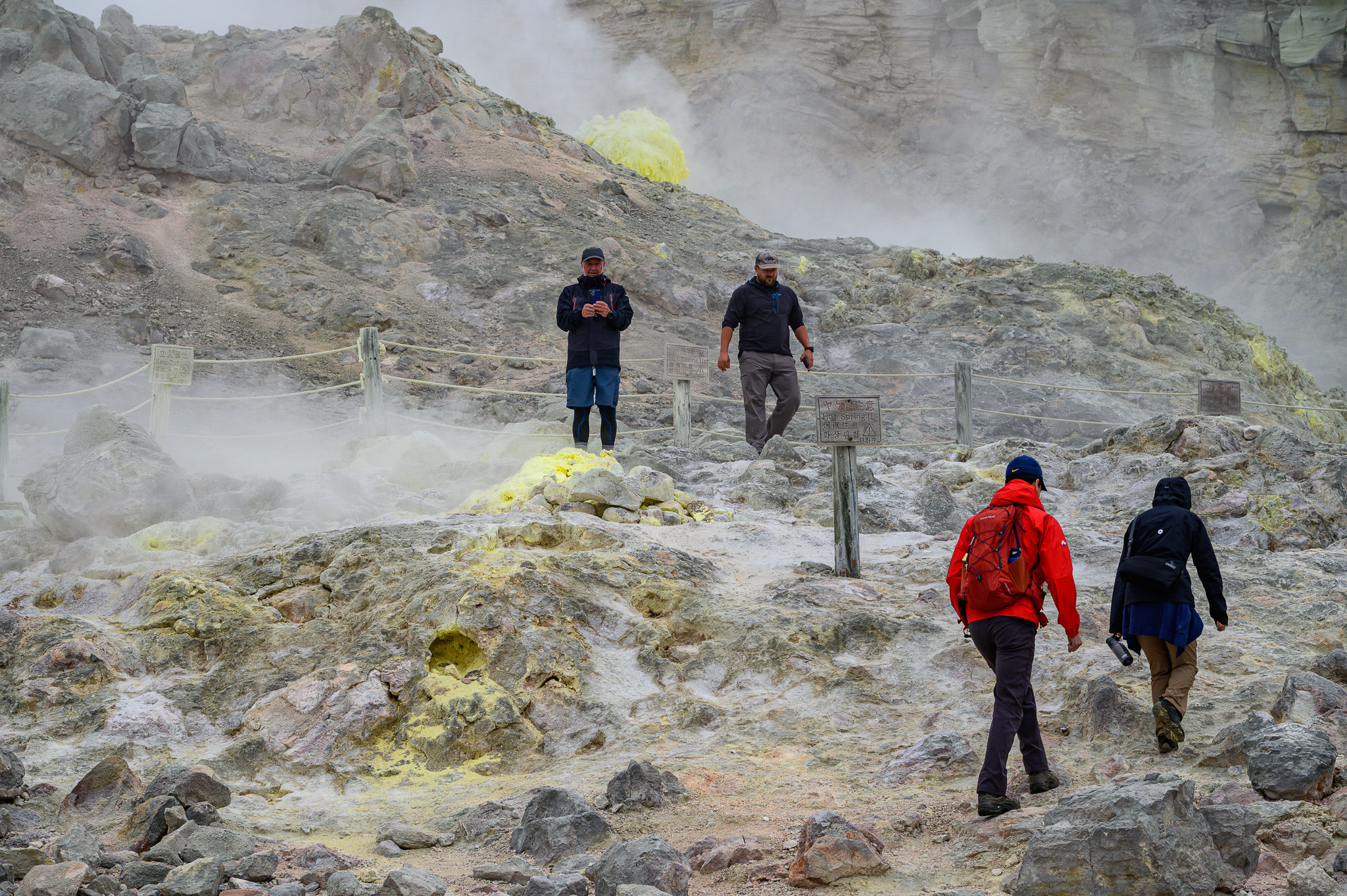 Four guides walk around Mt. Io's otherworldly landscape, dotted by sulfuric fumaroles.
