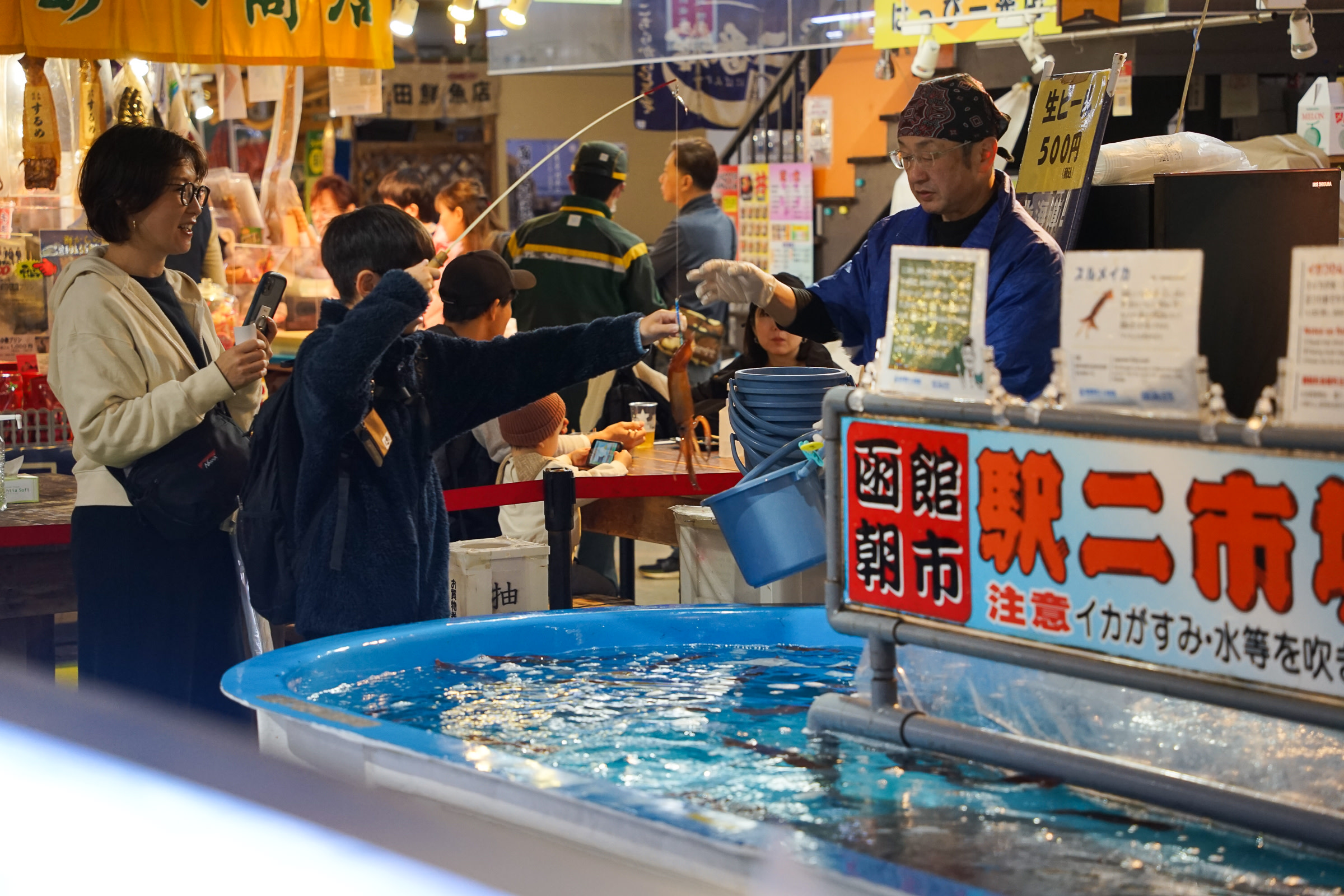 A large tub at Hakodate Morning Market full of live squid. Visitors are catching their own squid.
