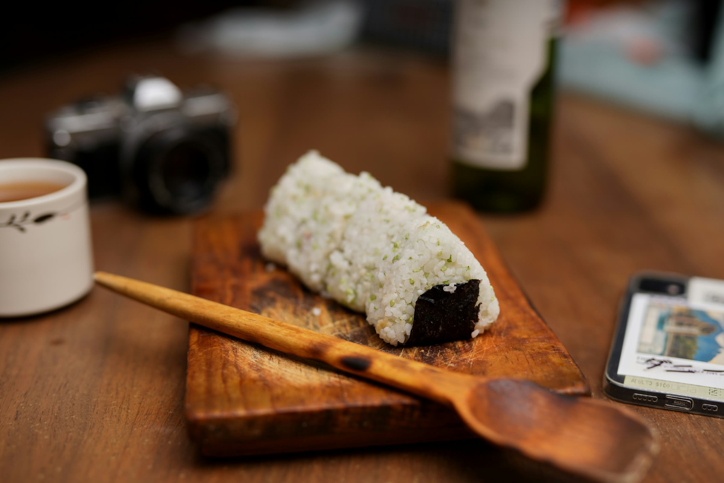 A line of four onigiri (rice balls with a seaweed wrapper) lined up on a wooden board.