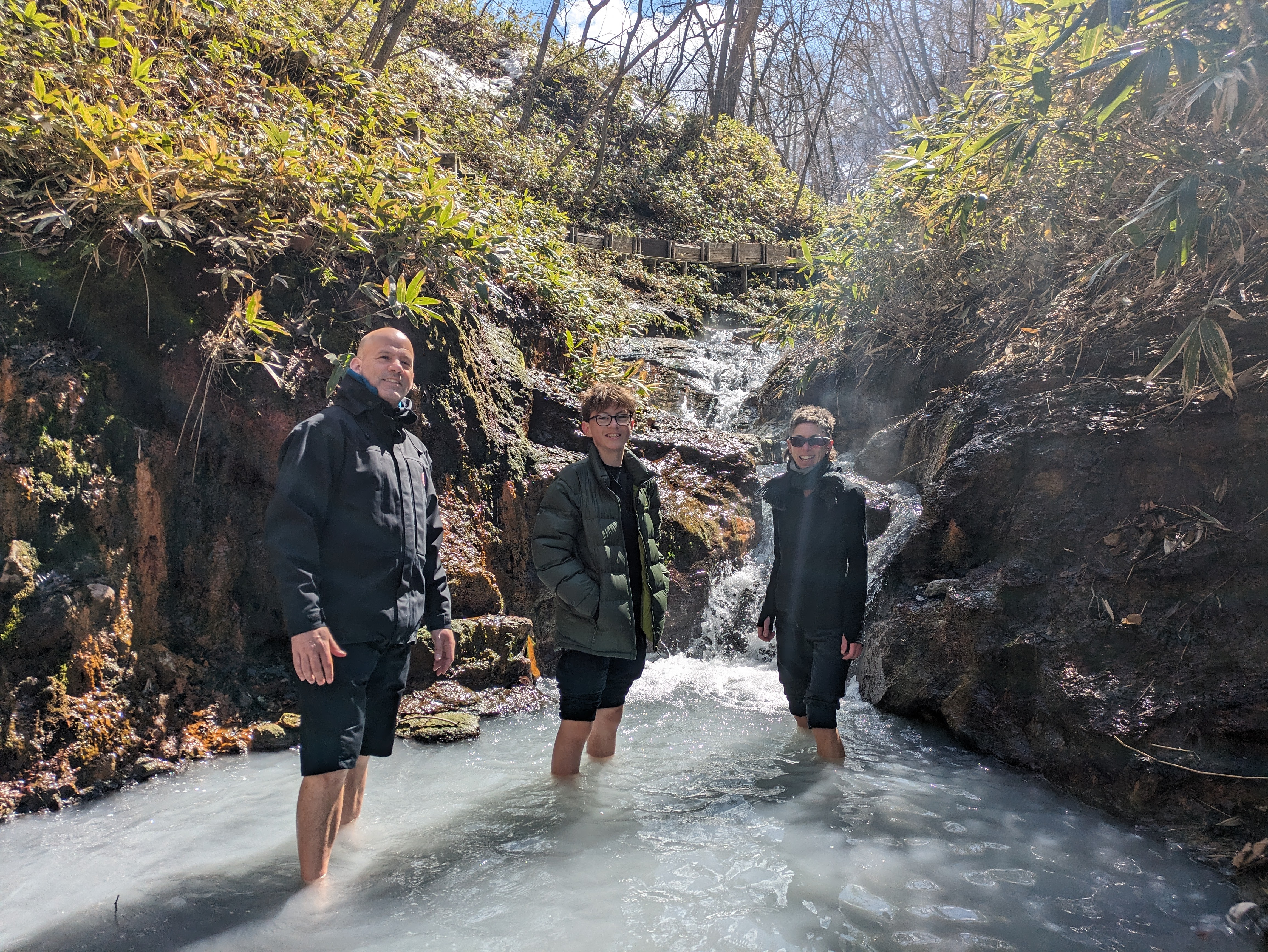 Three guests warm up their feet in Noboribetsu's opaque foot bath stream.