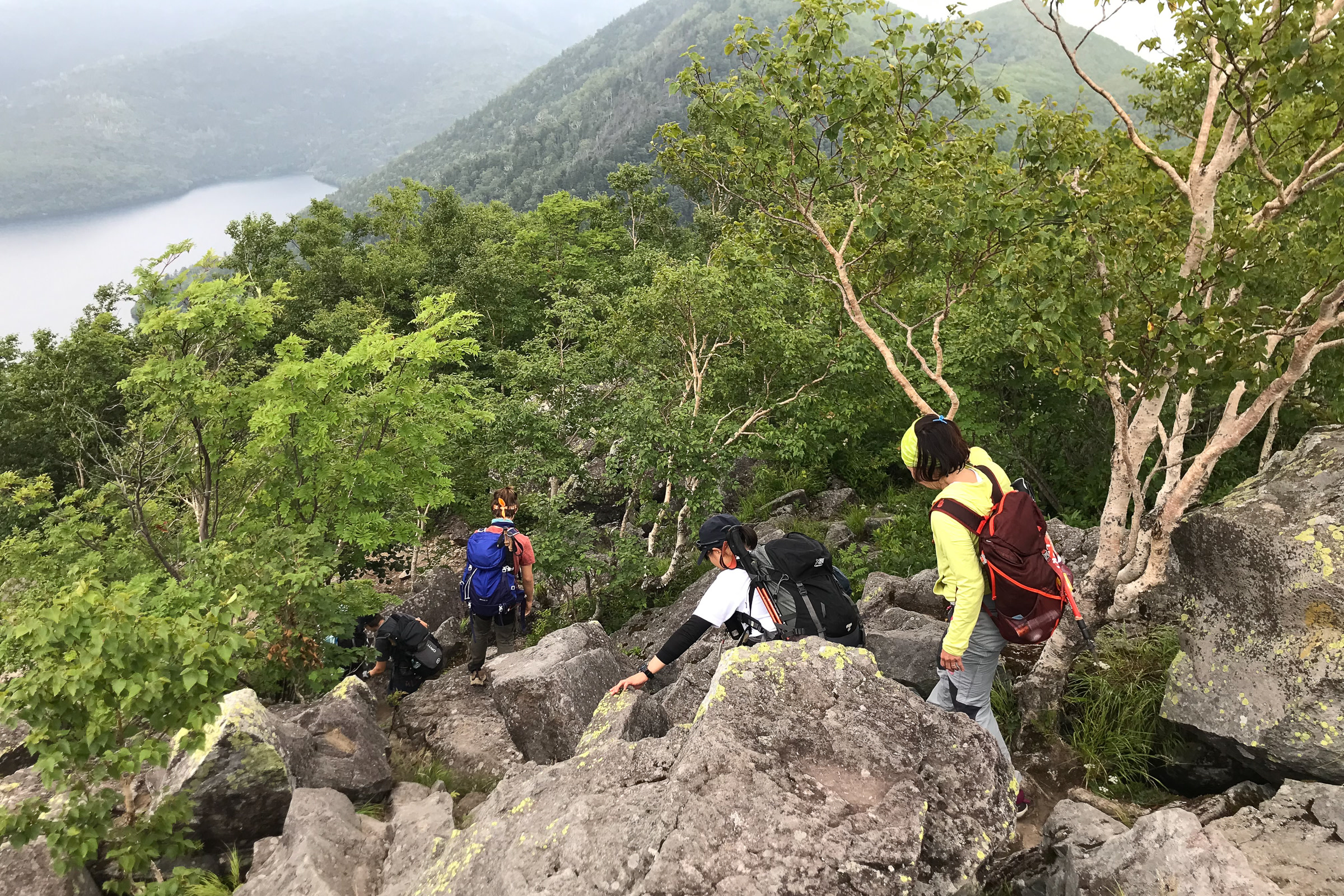Four hikers descend a mountain slope covered in boulders.