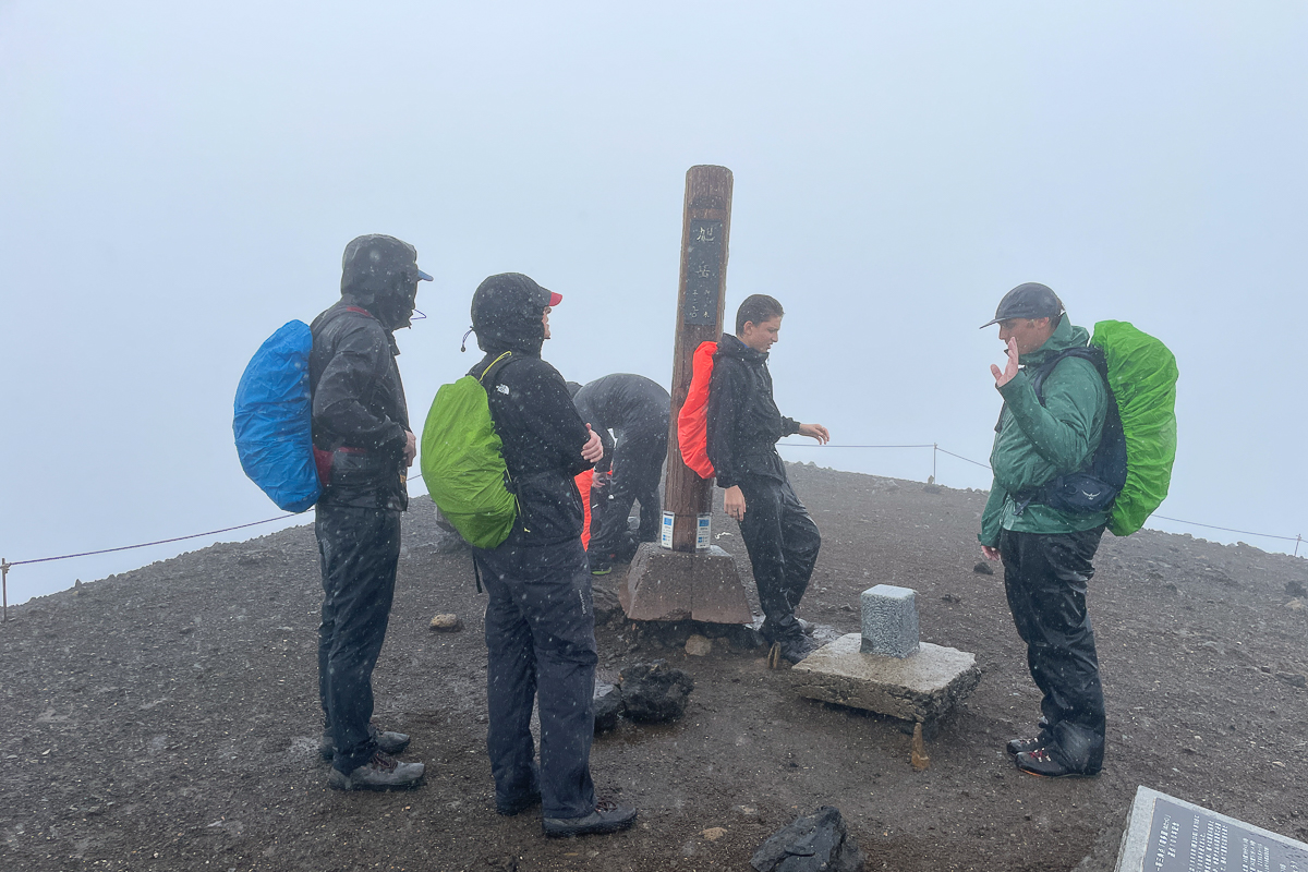 A group of hikers at the top of Mt Asahidake in the rain