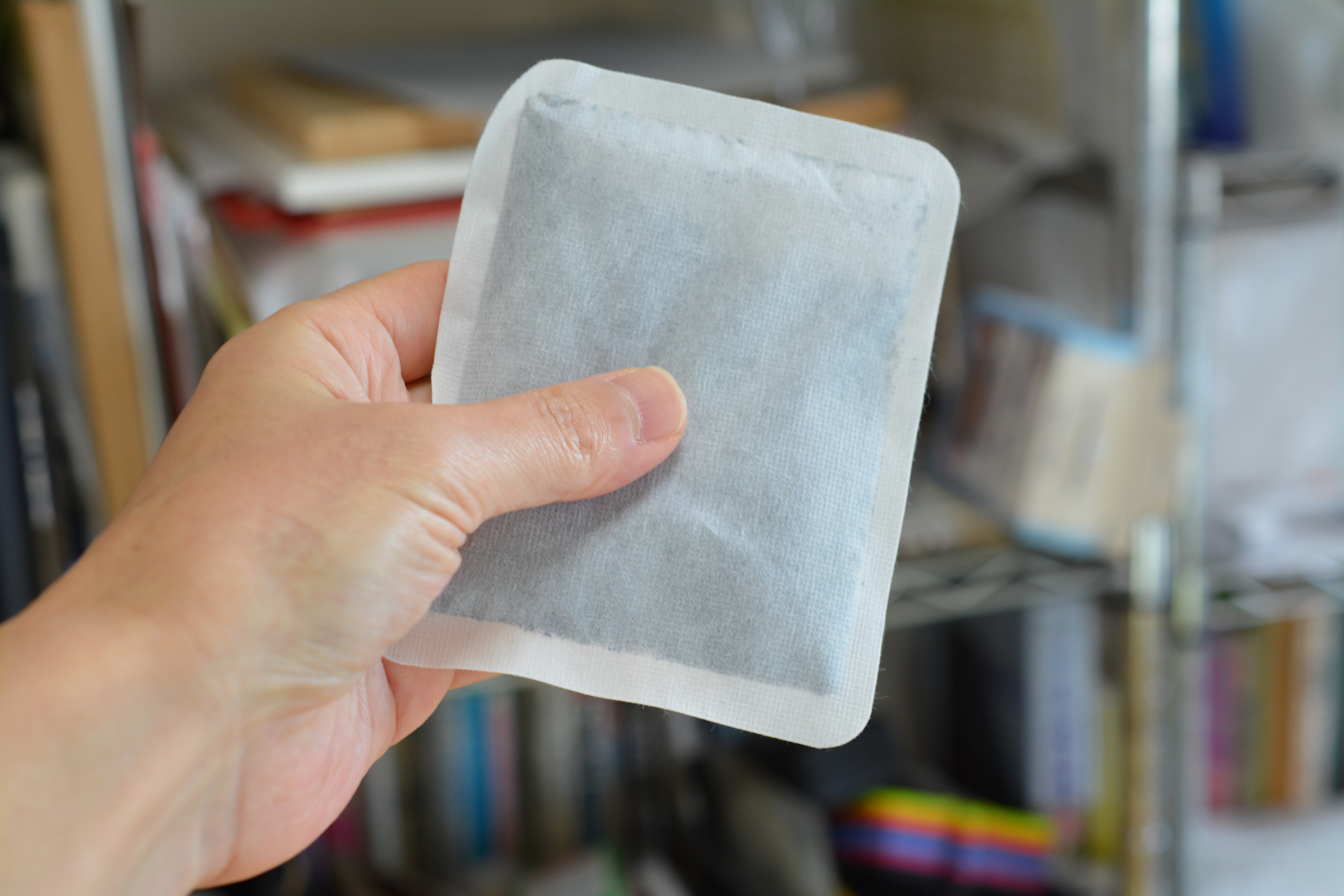 A hand holds a "kairo", a small hand-warming pouch.