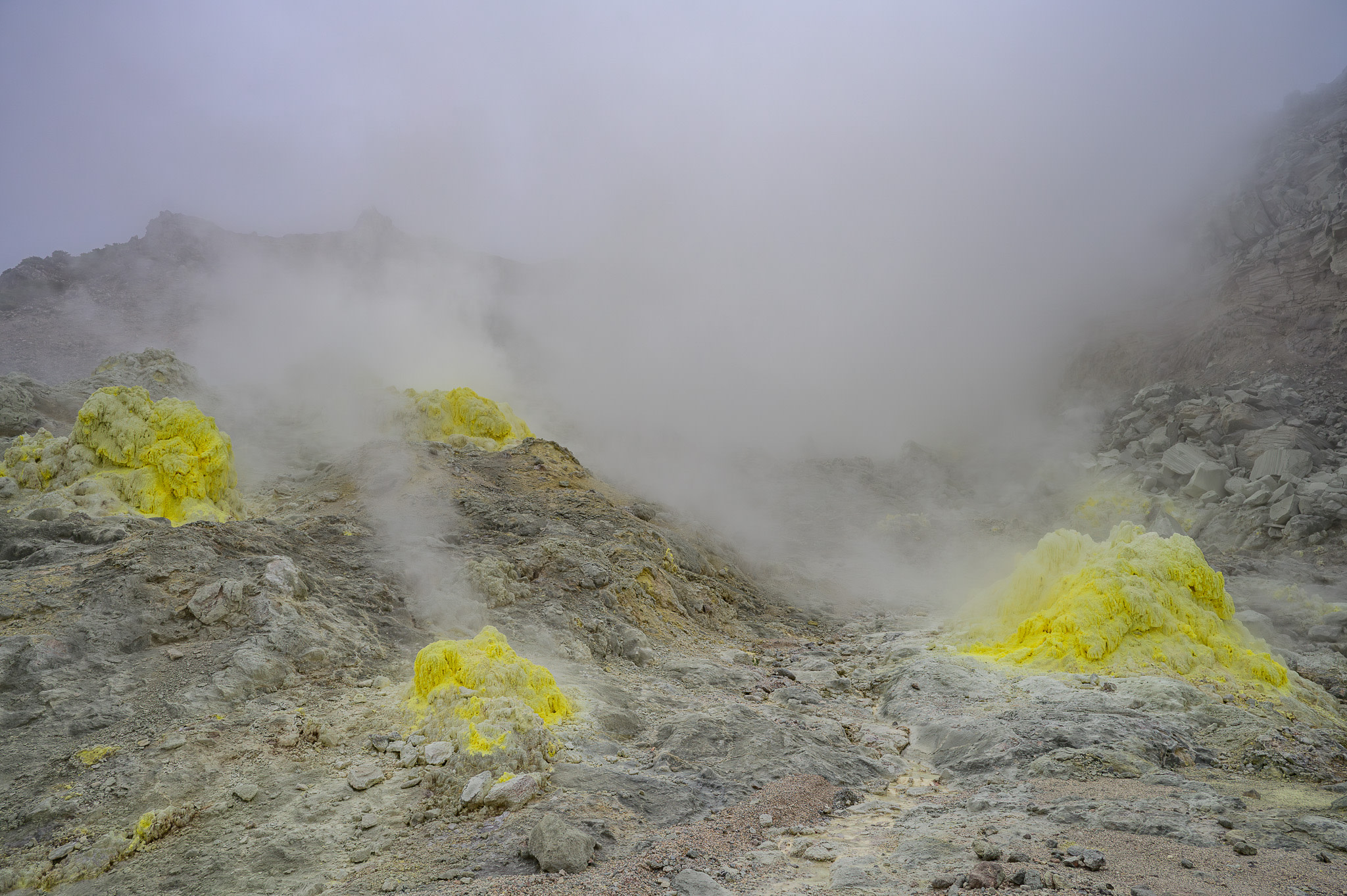 Several bright yellow fumaroles let out bellows of steam.