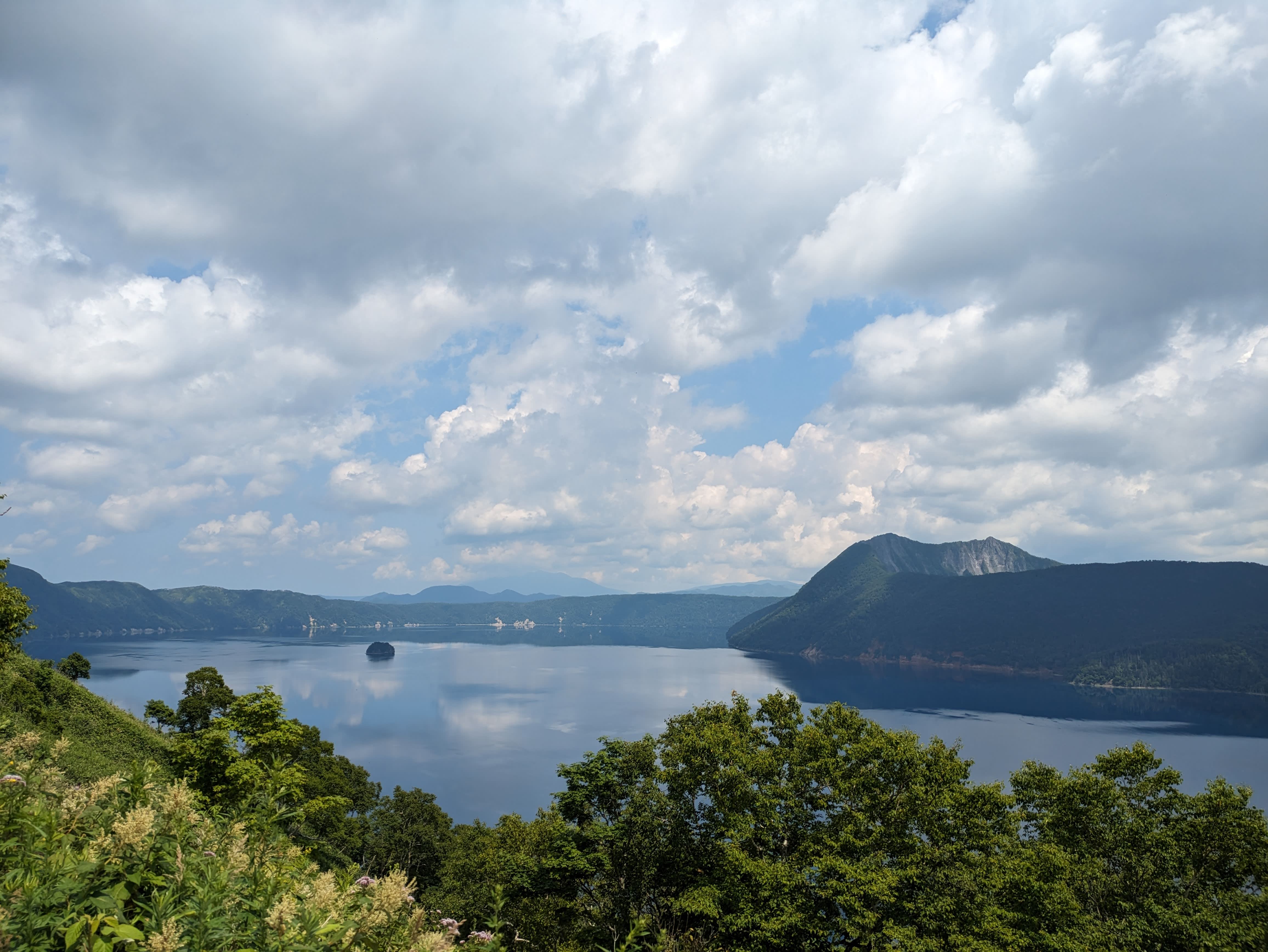 Lake Mashu's blue surface reflects the legions of cloud soaring across the sky.
