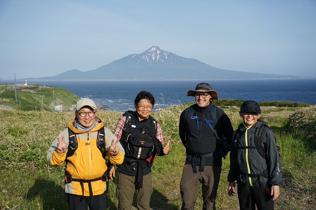 A group of hikers posing in front of Mount Rishiri